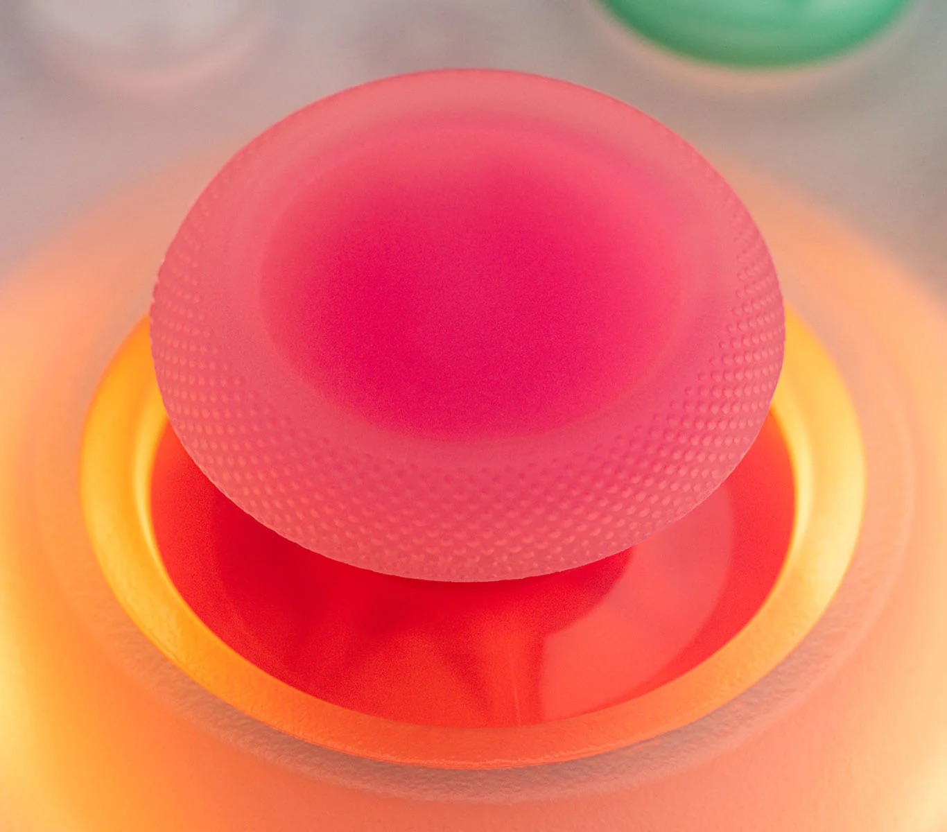 Primo piano di un joystick rosa con superficie testurizzata, circondato da illuminazione arancione.