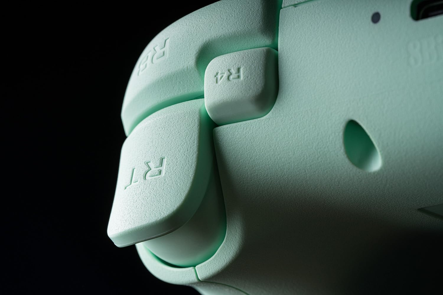 Zbliżenie jasnozielonego kontrolera do gier. Ostrość skupia się na przycisku R4 i spuście.