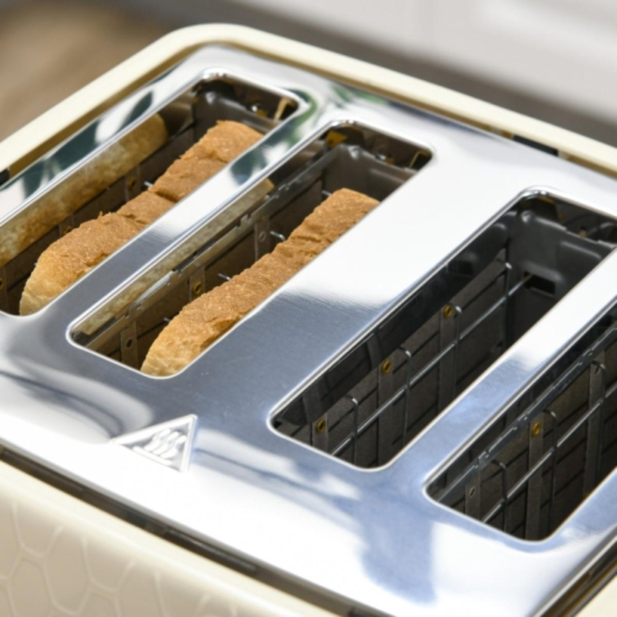 Nahaufnahme eines Toasters mit vier Schlitzen, zwei Toastscheiben darin. Der Toaster ist beige und metallisch.