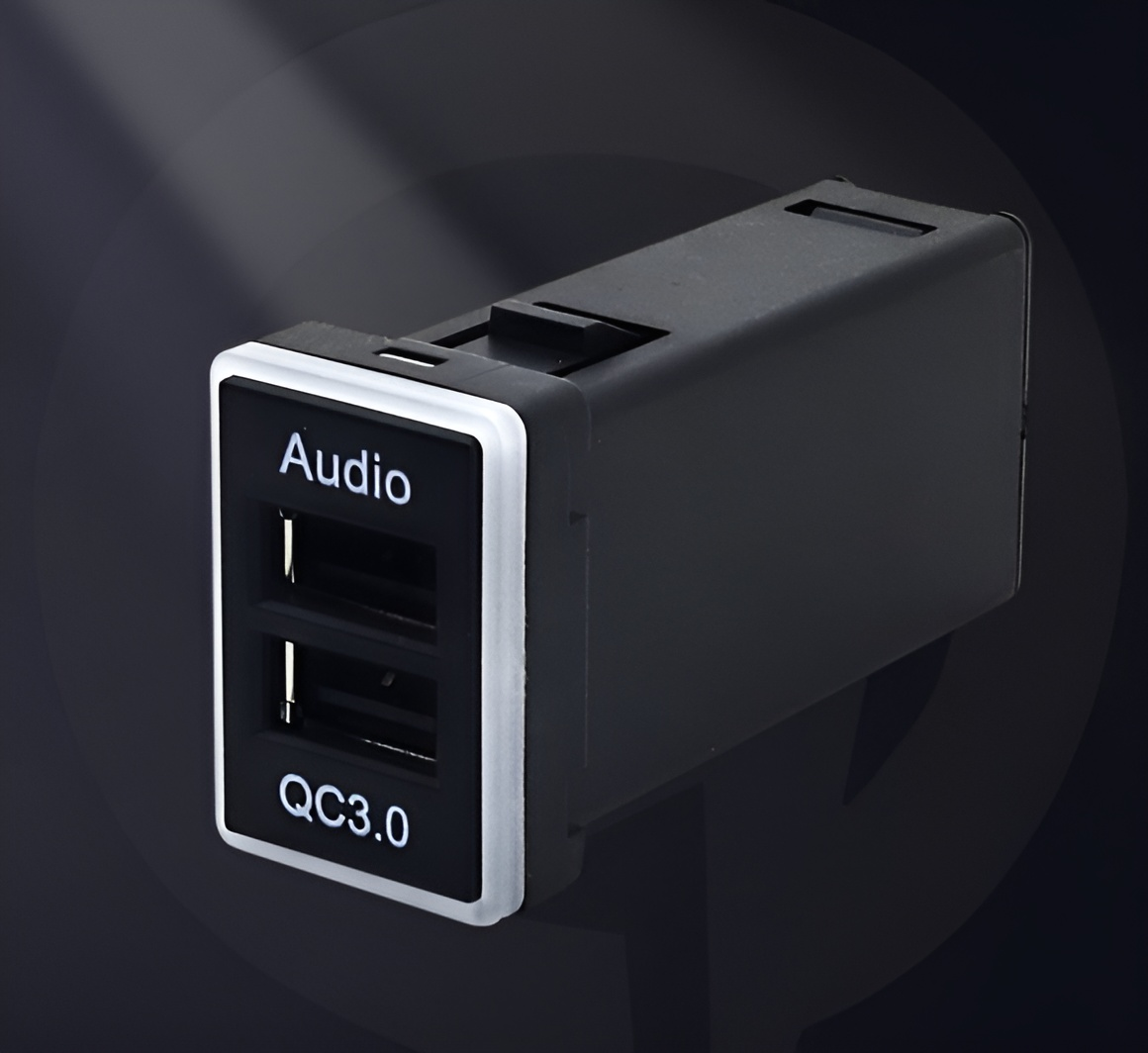 Schwarzes USB-Autoladegerät mit zwei USB-Anschlüssen, beschriftet mit 'Audio' und 'QC3.0', und einem weißen Rand.