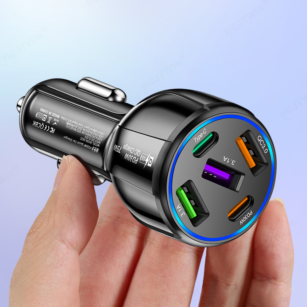 Hand hält ein schwarzes Autoladegerät mit mehreren Anschlüssen und einem blauen LED-Ring.