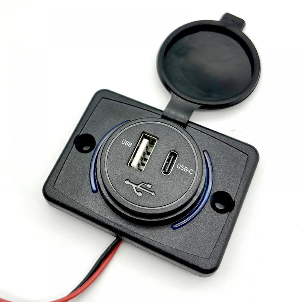 Ein schwarzer USB-Ladeanschluss mit einem USB-C-Anschluss. Er befindet sich in einem schwarzen Rahmen mit einer Abdeckung. Der Rahmen hat ein blaues Licht.