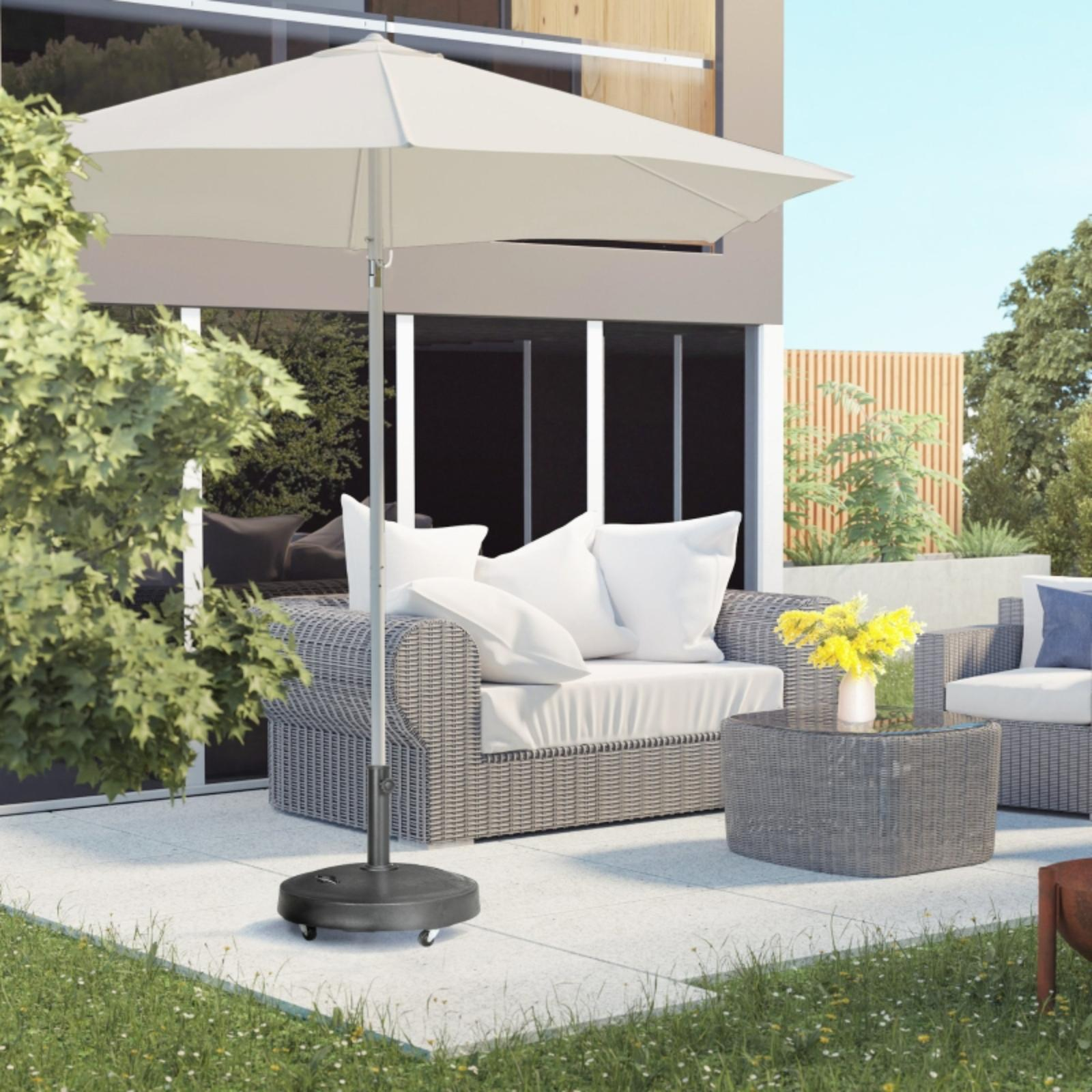 Sonnenschirm und -fuß auf Terrasse in der Nähe von Sitzgelegenheiten im Freien. Sonne, Grün und Haus im Hintergrund.