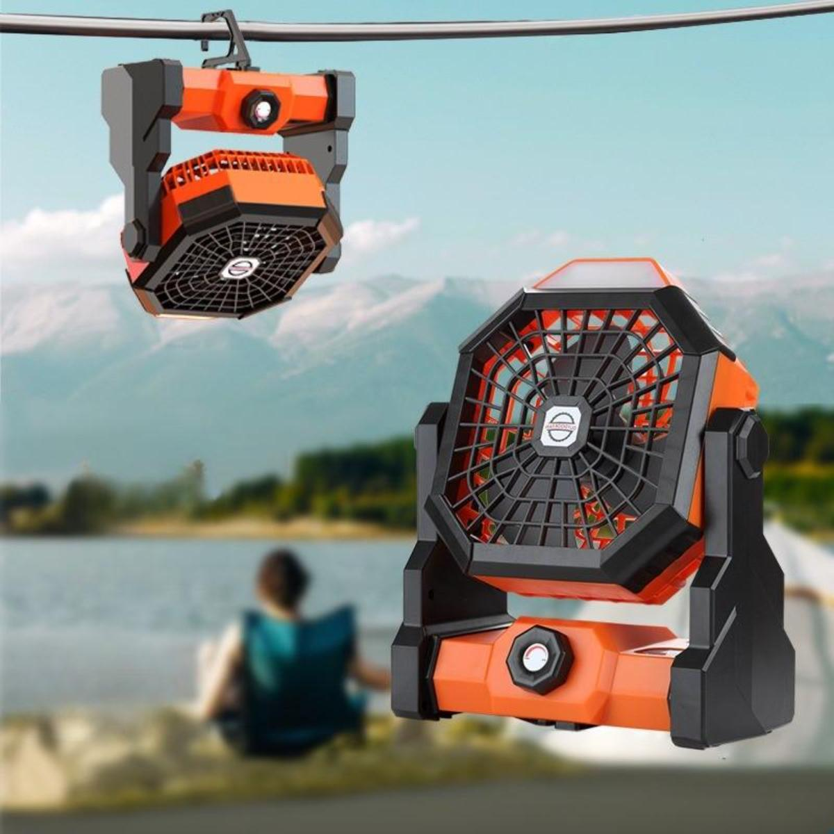 Zwei orangefarbene und schwarze Ventilatoren hängen an einem Kabel, mit See und Bergen im Hintergrund.