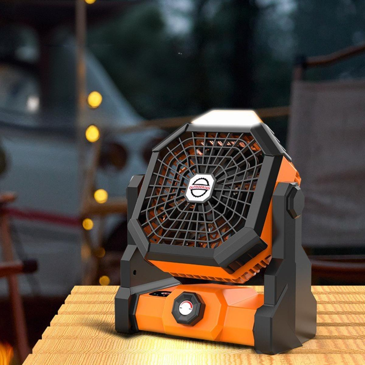 Oranger und schwarzer Ventilator auf einem Holztisch mit unscharfem Hintergrund.