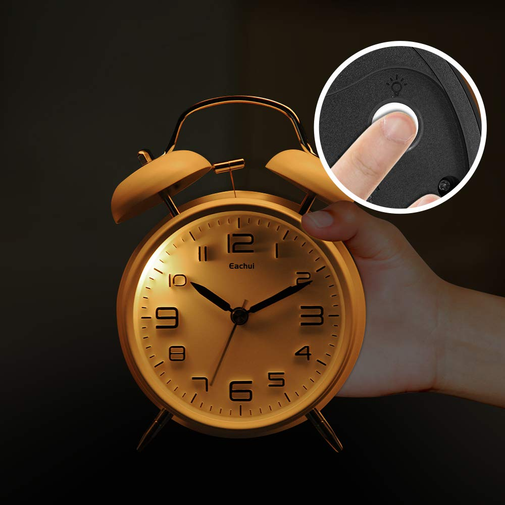 Ein goldener Wecker mit einem Finger, der einen Knopf drückt. Der Hintergrund ist dunkel.