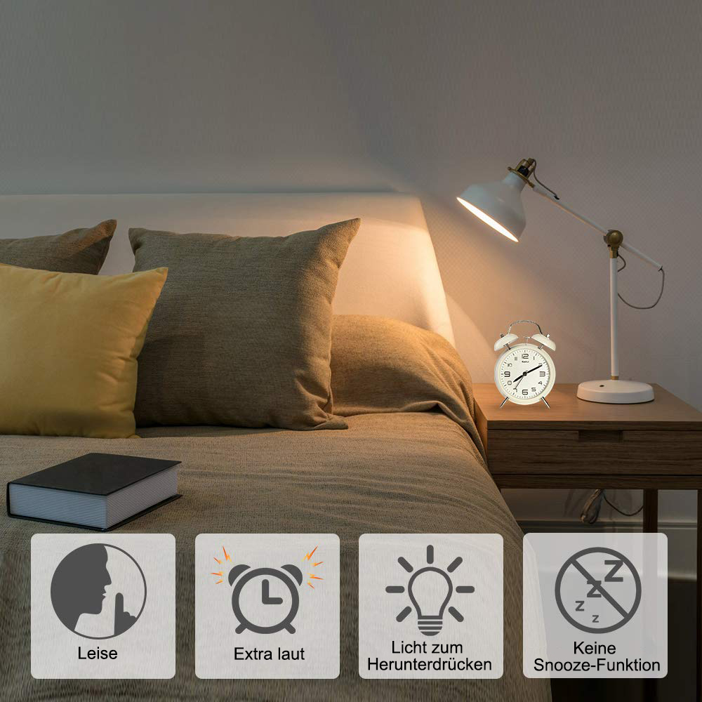 Bett-Szene mit Lampe, Wecker, Buch und Kissen. Im Hintergrund eine Wand.