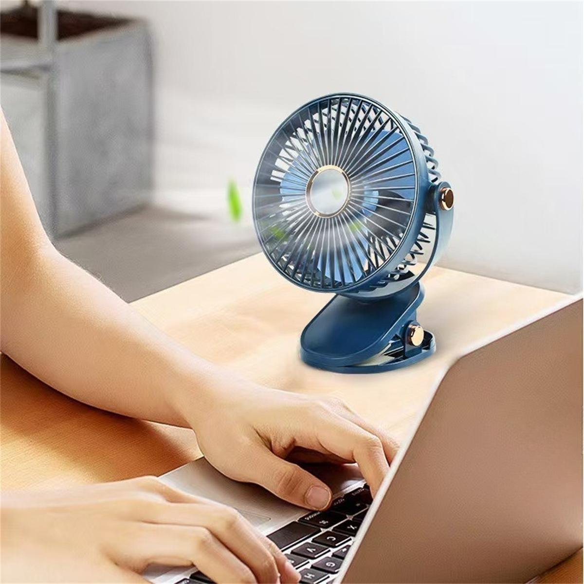 Eine Person, die einen Laptop benutzt, mit einem blauen Ventilator auf dem Schreibtisch, an der Oberfläche befestigt.