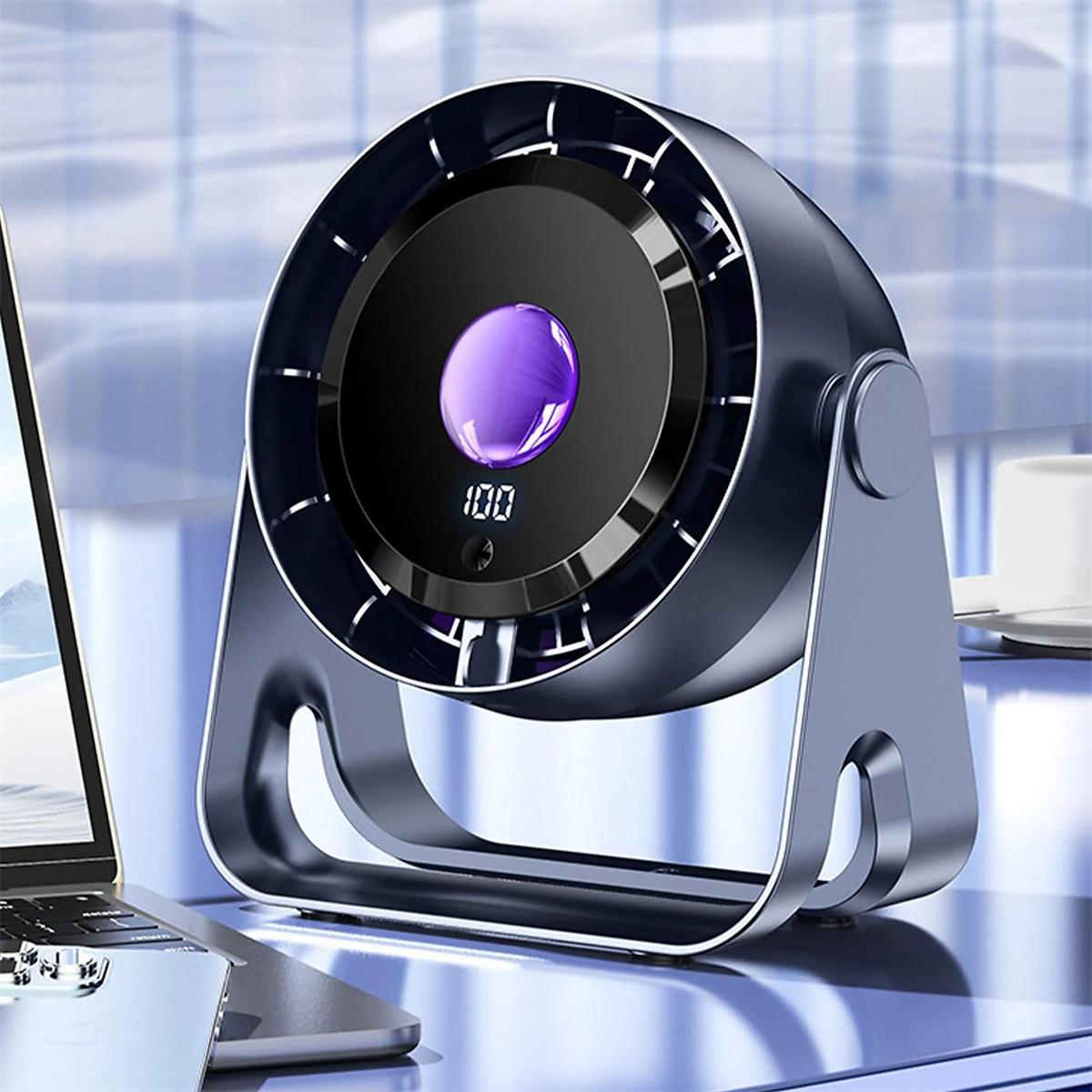 Ein dunkelblauer Ventilator auf einem Schreibtisch mit Laptop und Tasse. Er hat eine digitale Anzeige mit 100.