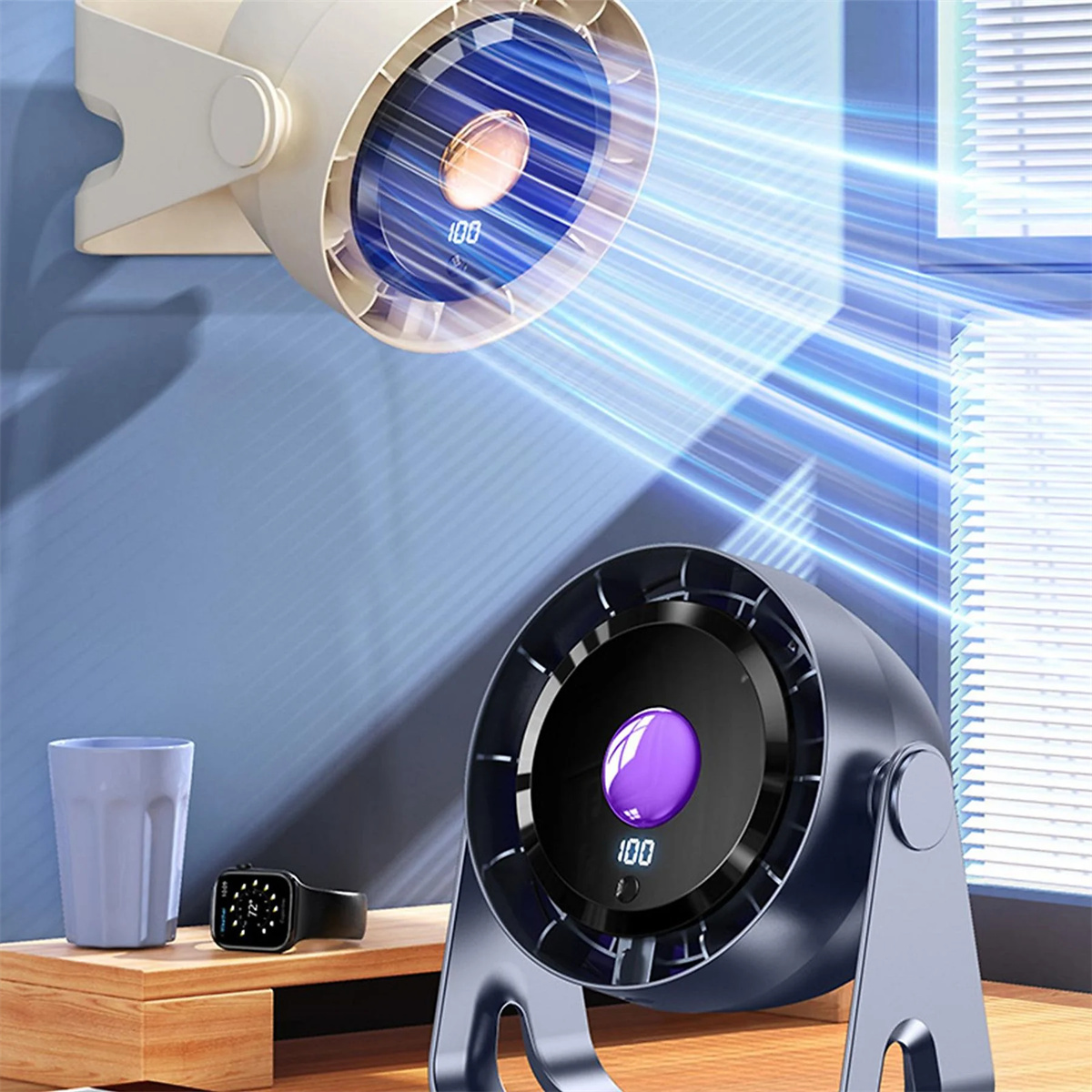 Ein blau-schwarzer Ventilator mit digitaler Anzeige 100. Becher, Uhr und Tisch im Vordergrund.