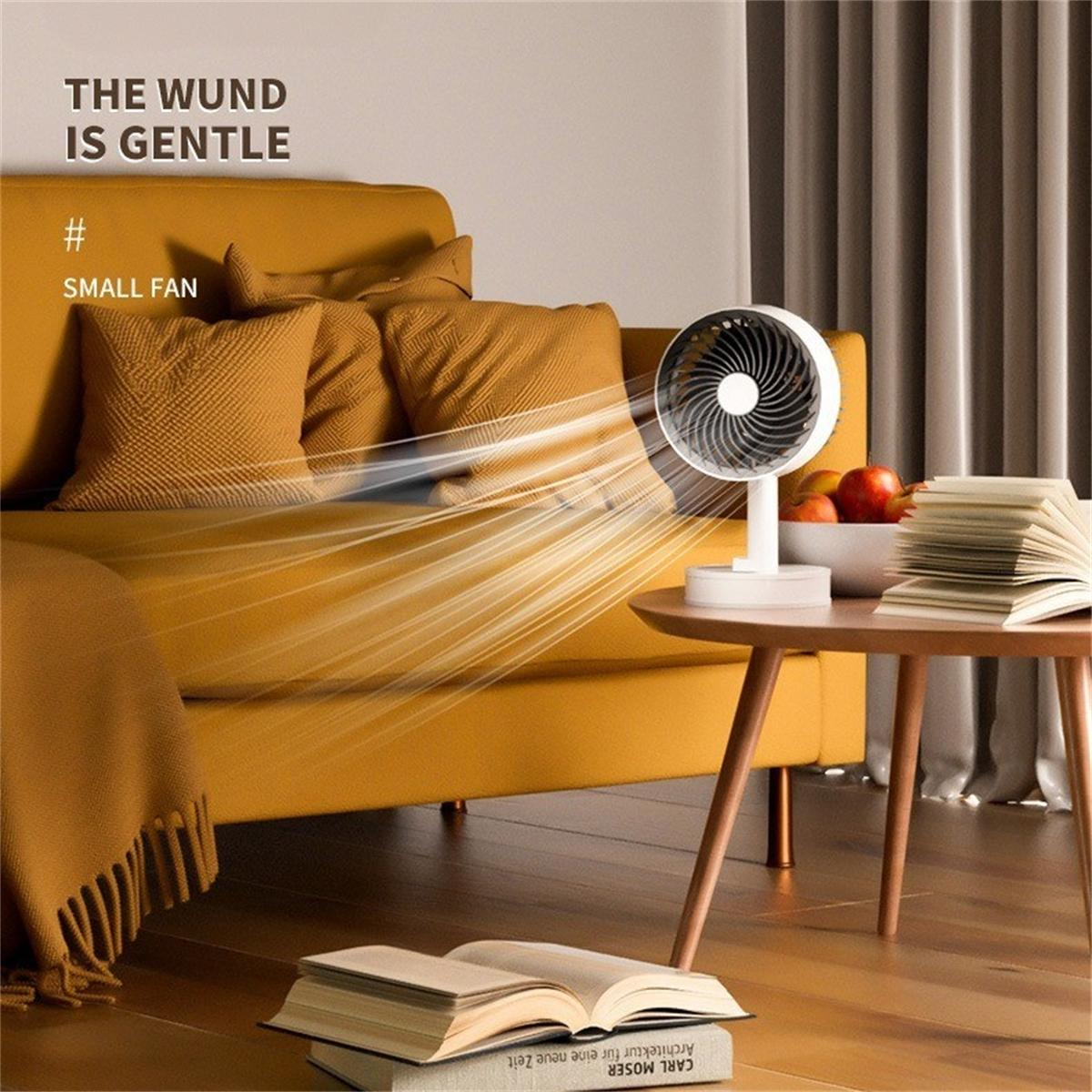 Weißer Ventilator auf Tisch, pustend, neben Büchern und gelbem Sofa.