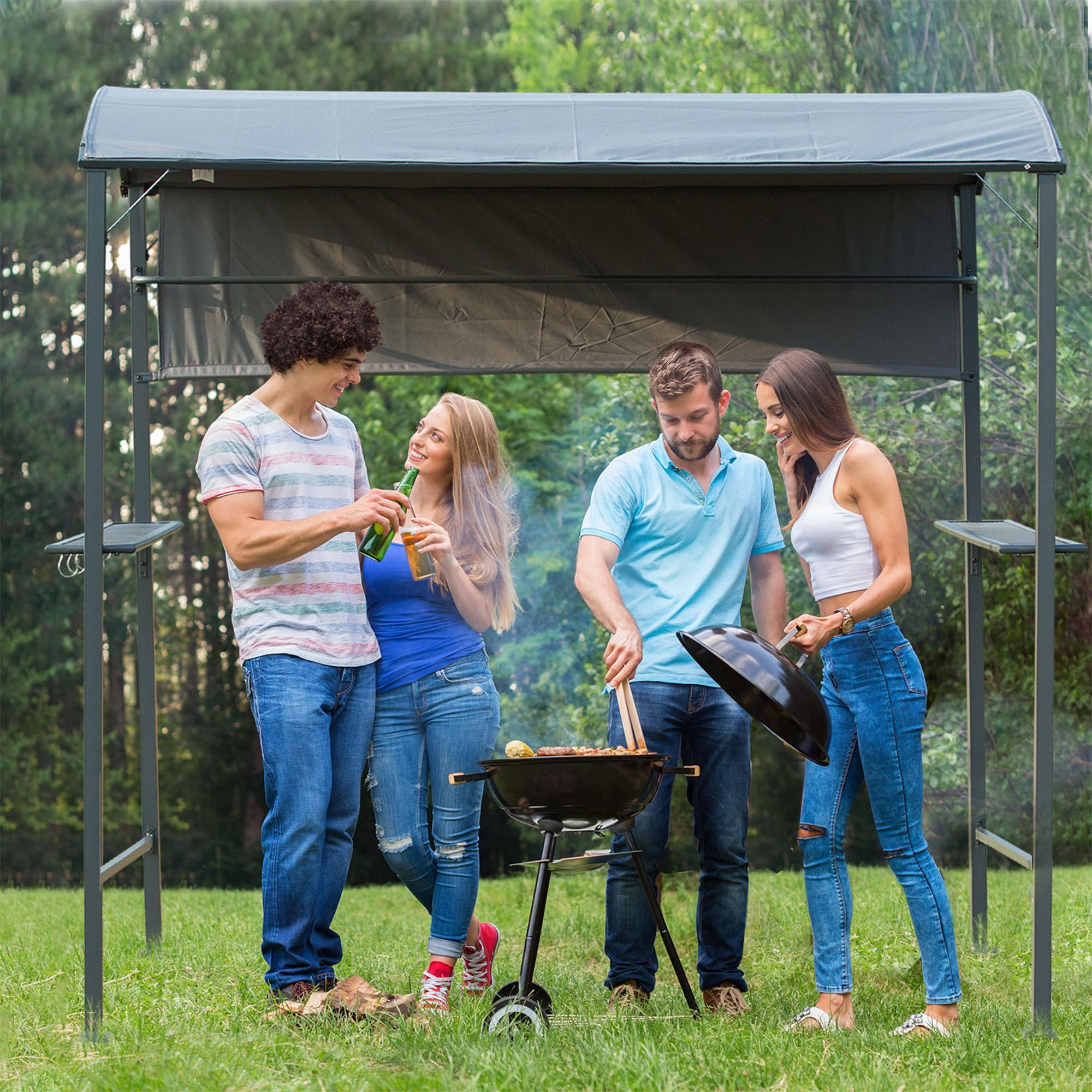 Vier Personen grillen im Freien unter einem Vordach. Mit Grill, Essen und Getränken.