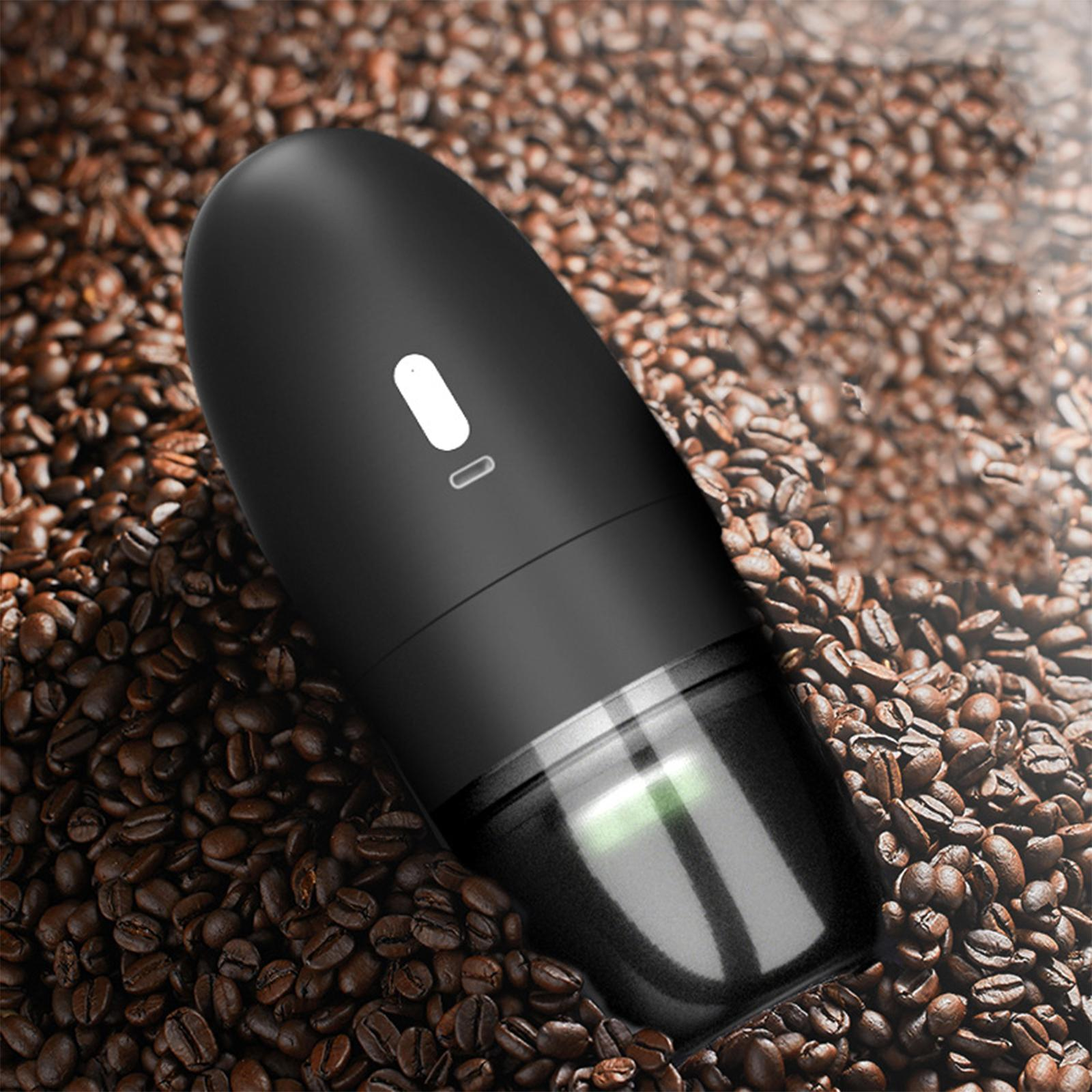 Schwarzer elektrischer Mahlwerk auf Kaffeebohnen. Der Mahlwerk ist oval und hat einen klaren Boden.
