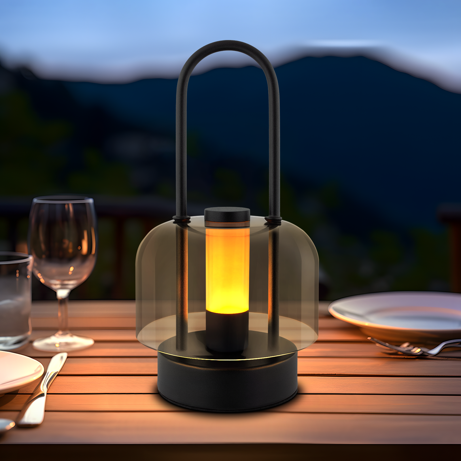 Czarna latarnia z uchwytem, na stole ze szklankami i talerzami, góry w tle.