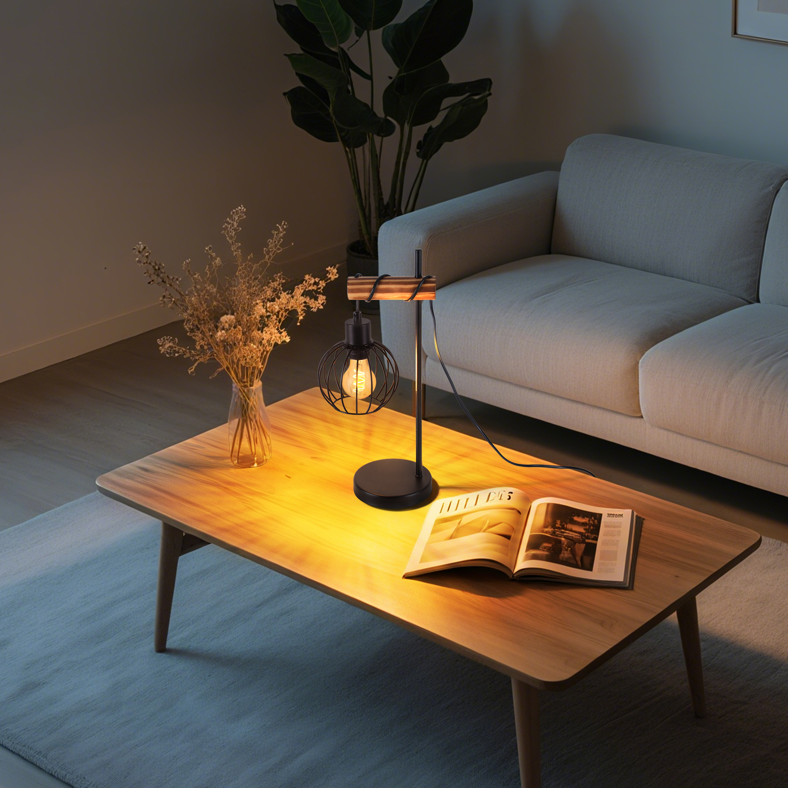 Lampa na drewnianym stole z książką i kwiatami. W tle sofa.