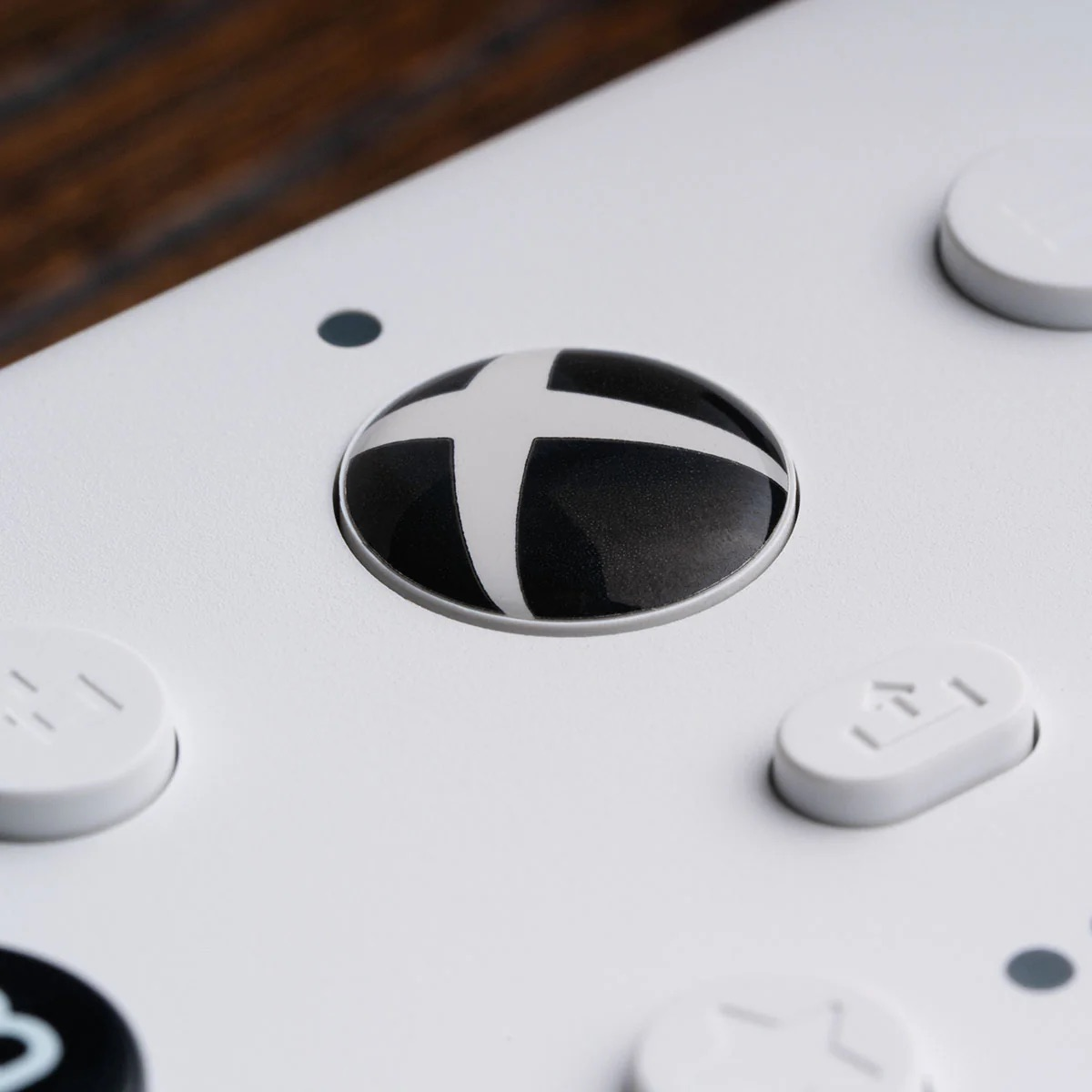 Primer plano del botón del logotipo de Xbox en un mando blanco. El logo es negro y blanco.