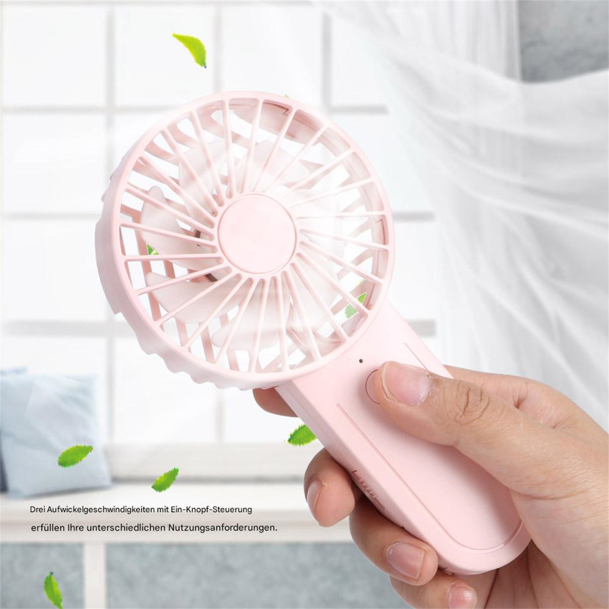 Eine Hand hält einen pinkfarbenen Handventilator. Blätter und ein Fenster sind im Hintergrund.