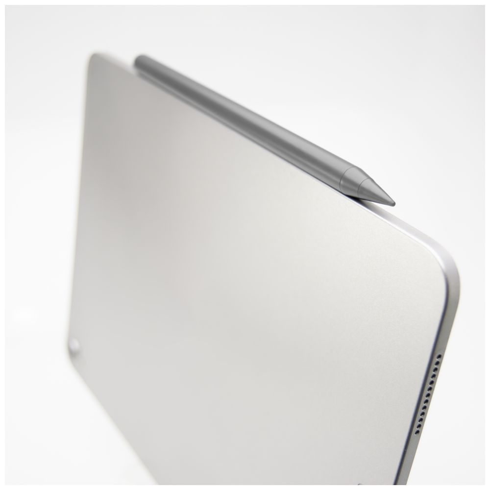 Ein grauer Stylus-Stift ist magnetisch an einem silbernen Tablet befestigt. Weißer Hintergrund.