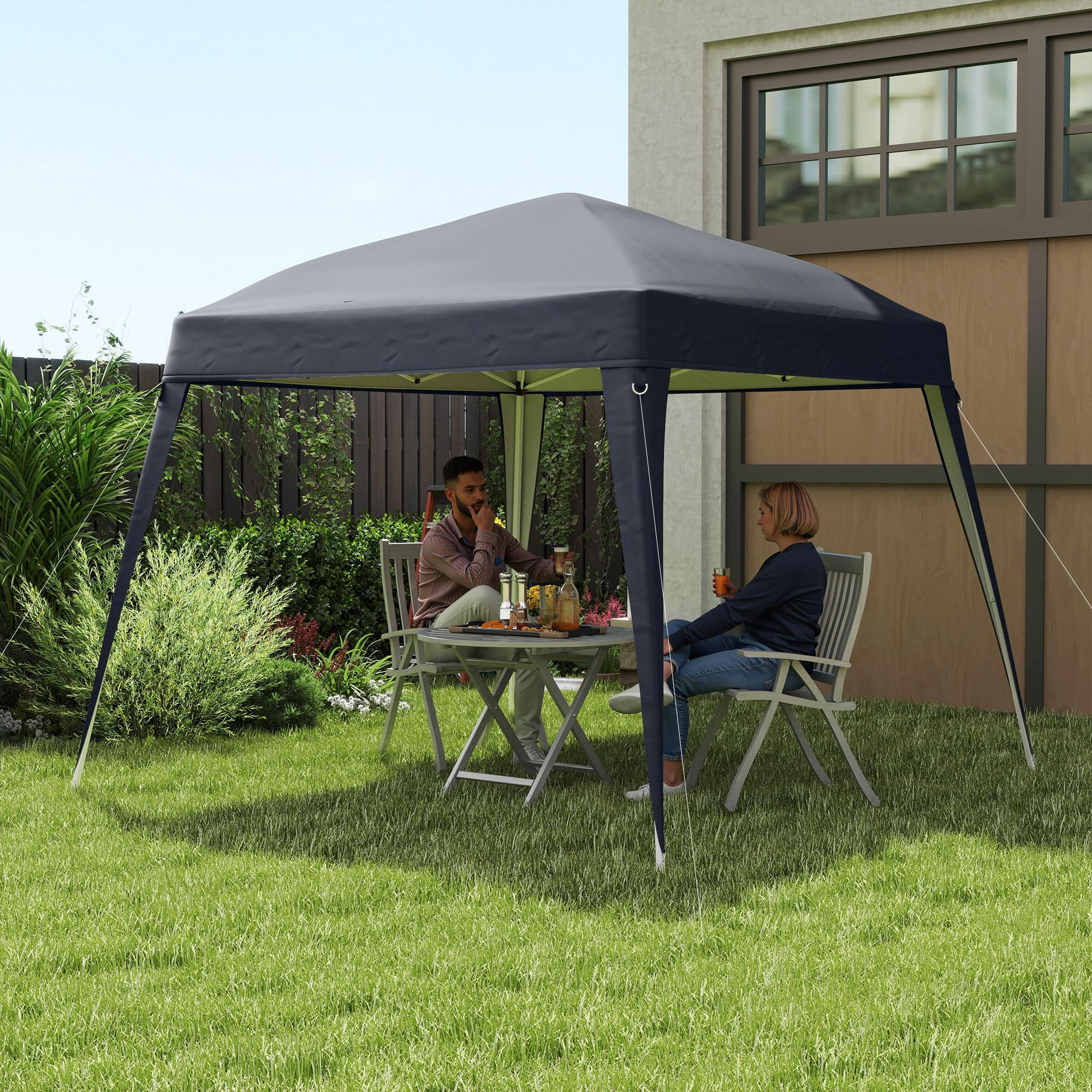Zwei Personen sitzen an einem Tisch unter einem dunkelgrauen Pavillon in einem Garten. Grünes Gras umgibt sie.