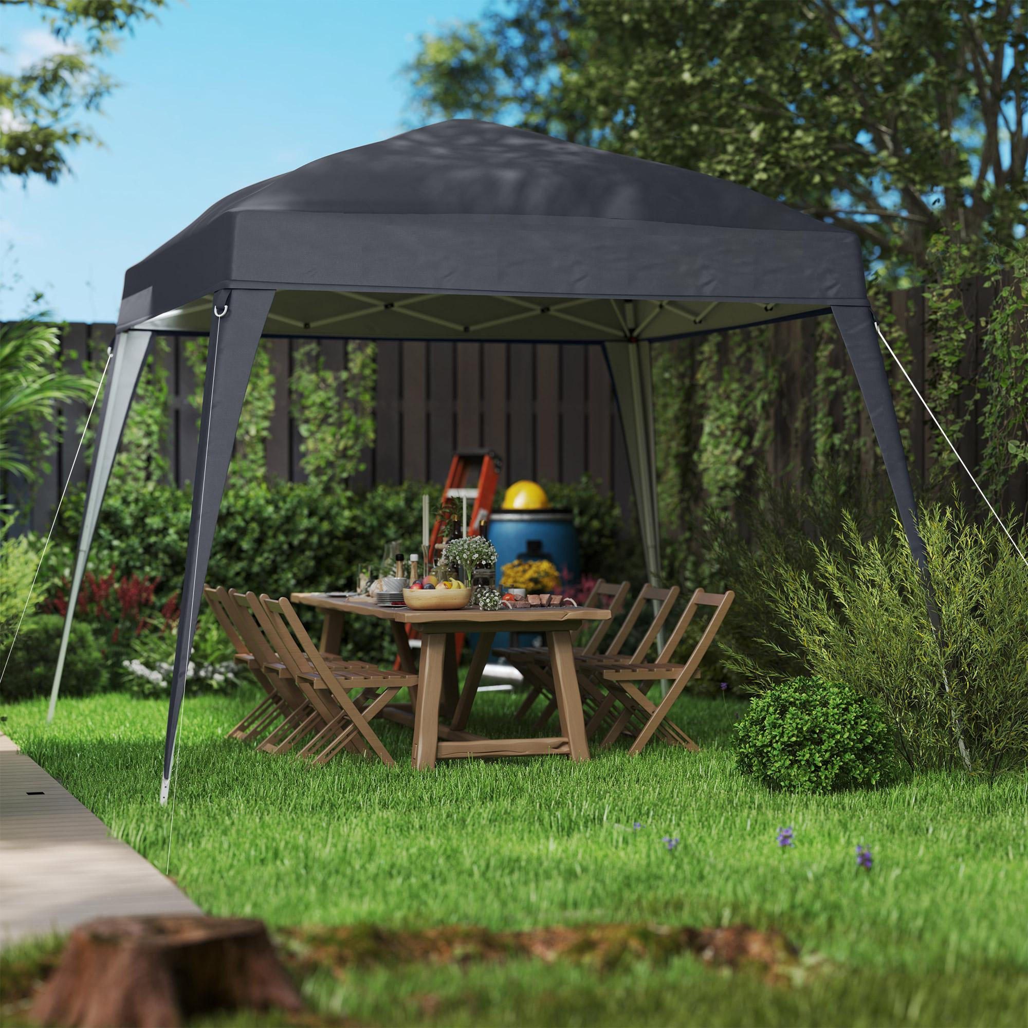 Ein schwarzer Pavillon mit einem Tisch, der für eine Mahlzeit auf einer Rasenfläche gedeckt ist. Es gibt eine Leiter, ein Fass und Bäume.