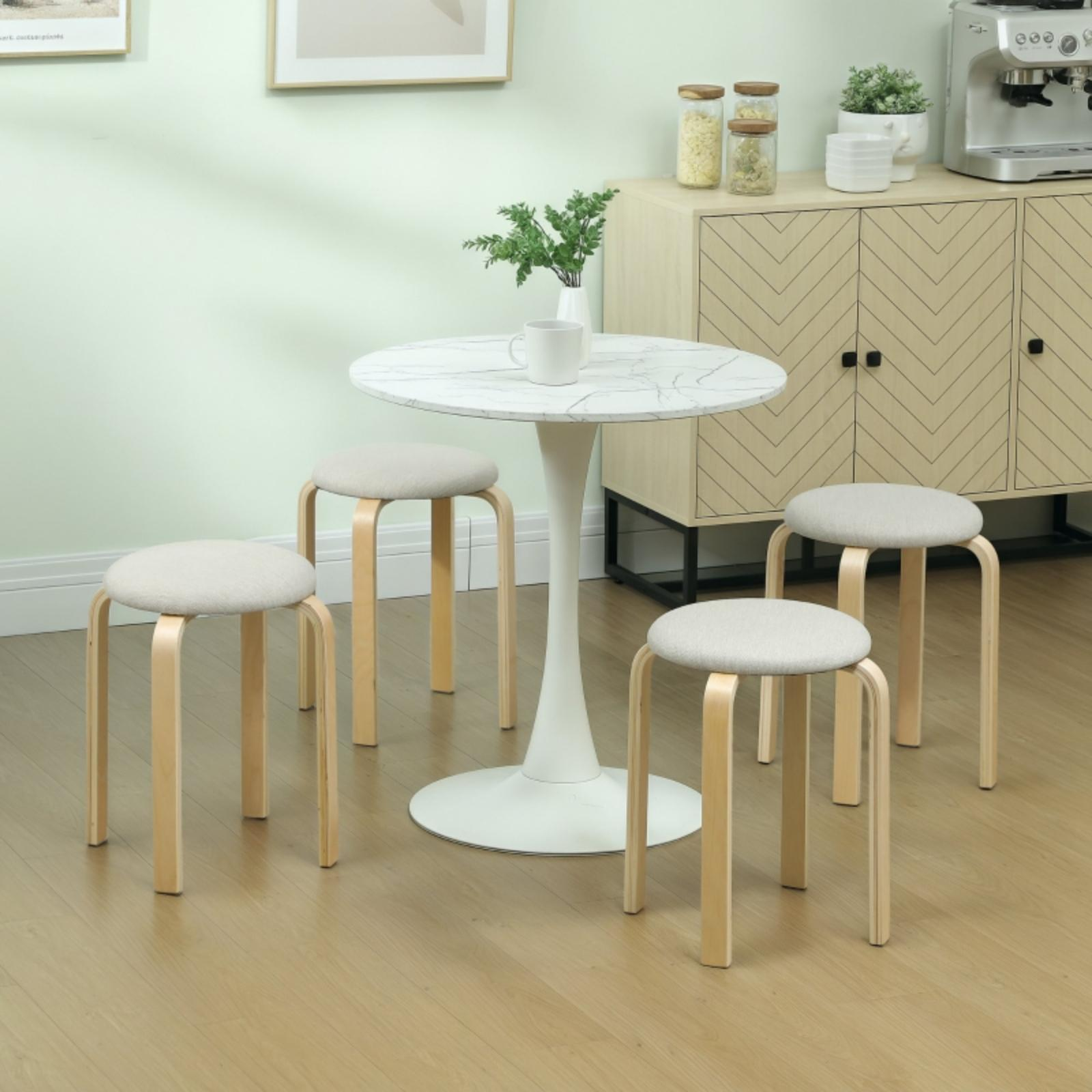 Vier helle Holzstühle um einen weißen runden Tisch. Eine Vase mit Grün steht in der Mitte des Tisches.