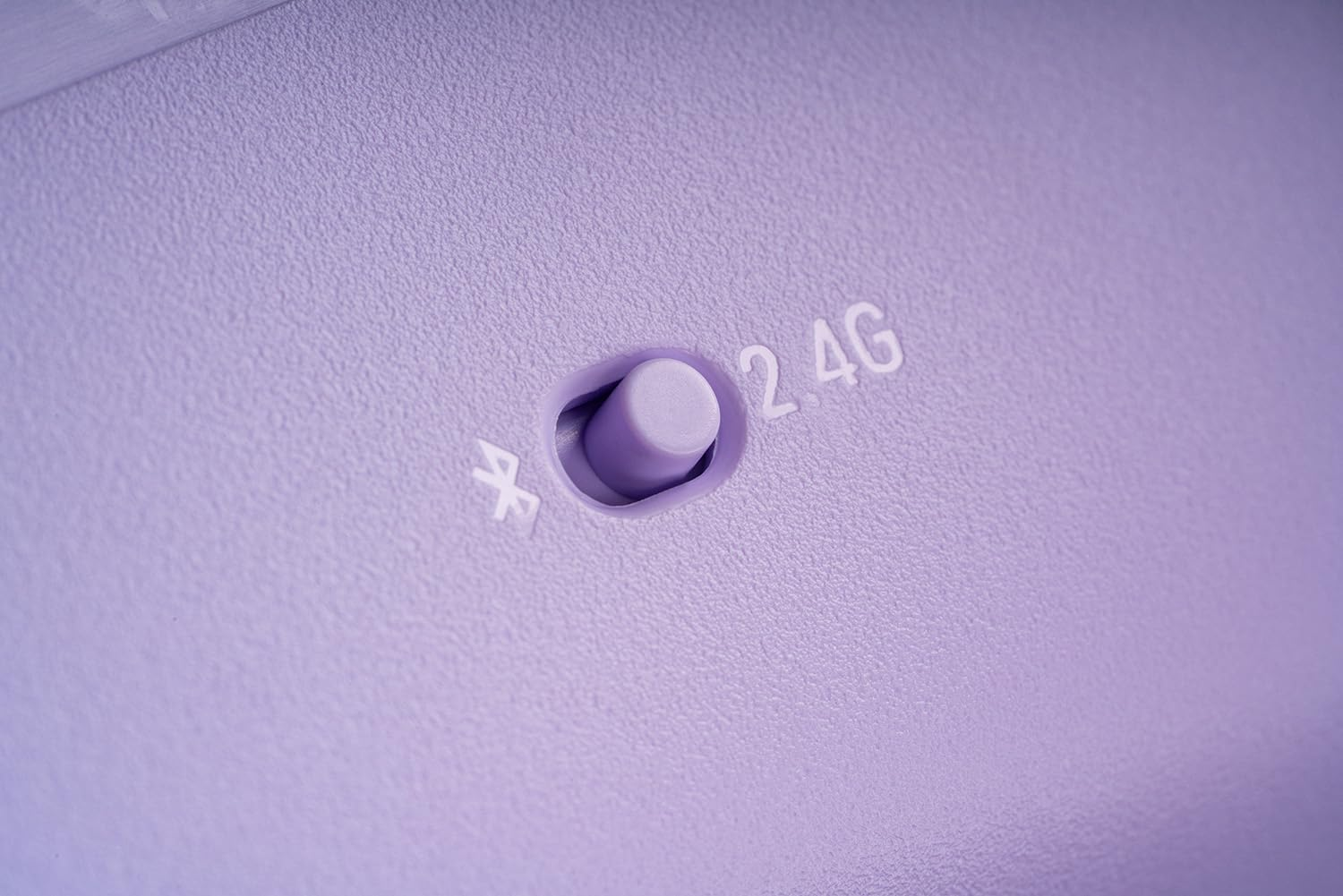 Zbliżenie przycisku z tekstem Bluetooth i 2.4G na jasnofioletowym kontrolerze do gier.