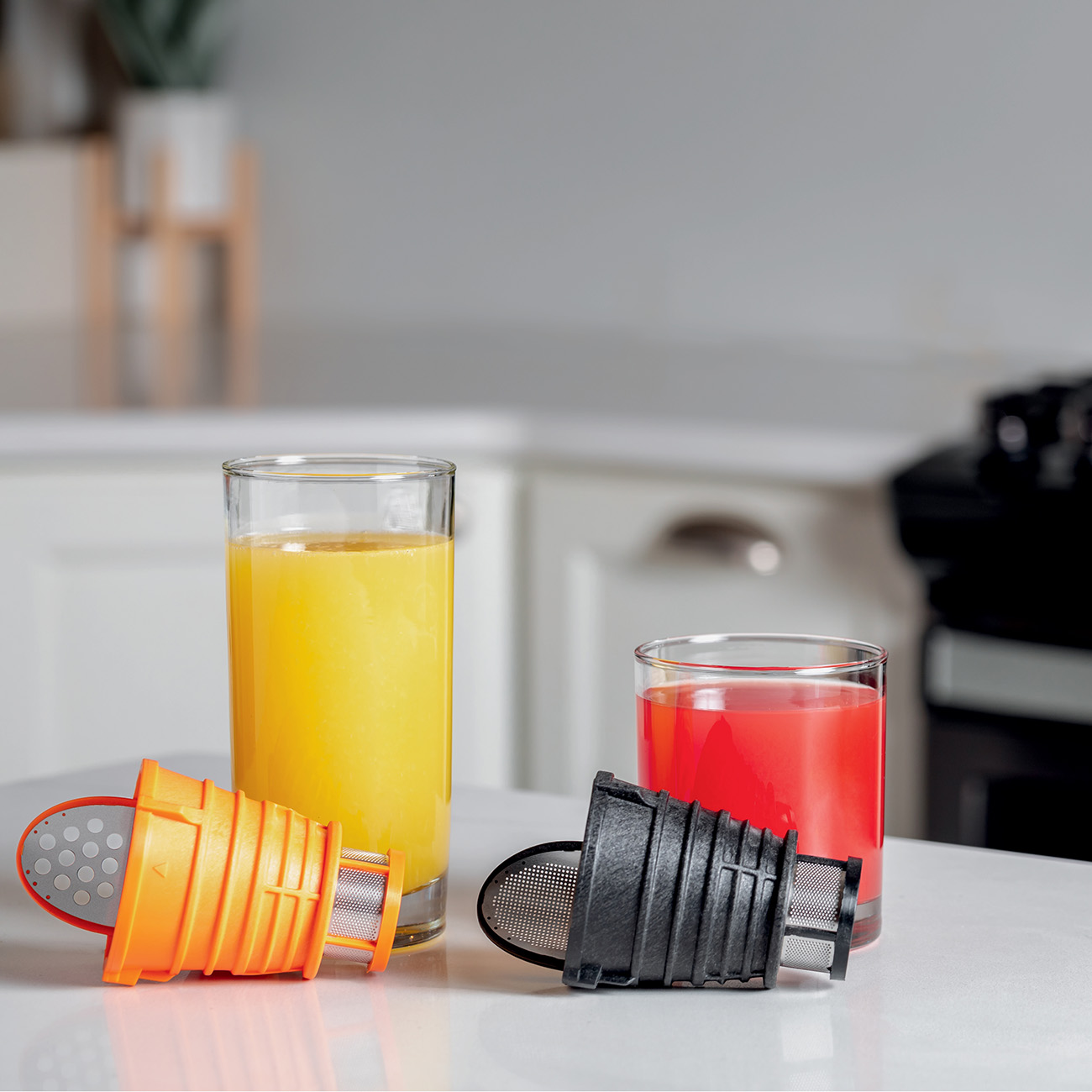 Glasses of juice. Orange juice and red juice. Juicer parts are in front.
