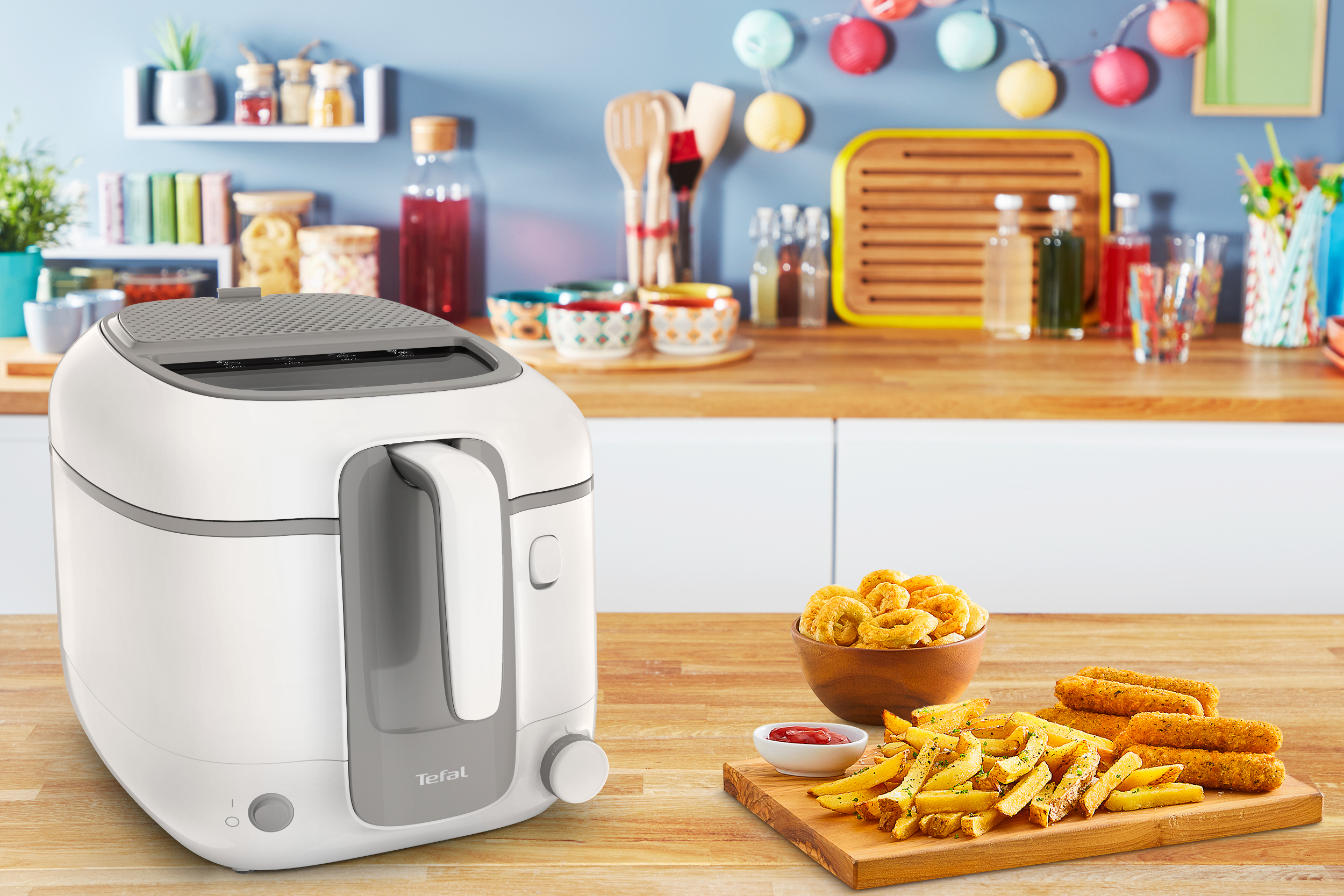 Freidora Tefal blanca en mostrador, con comida frita y fondo de cocina.