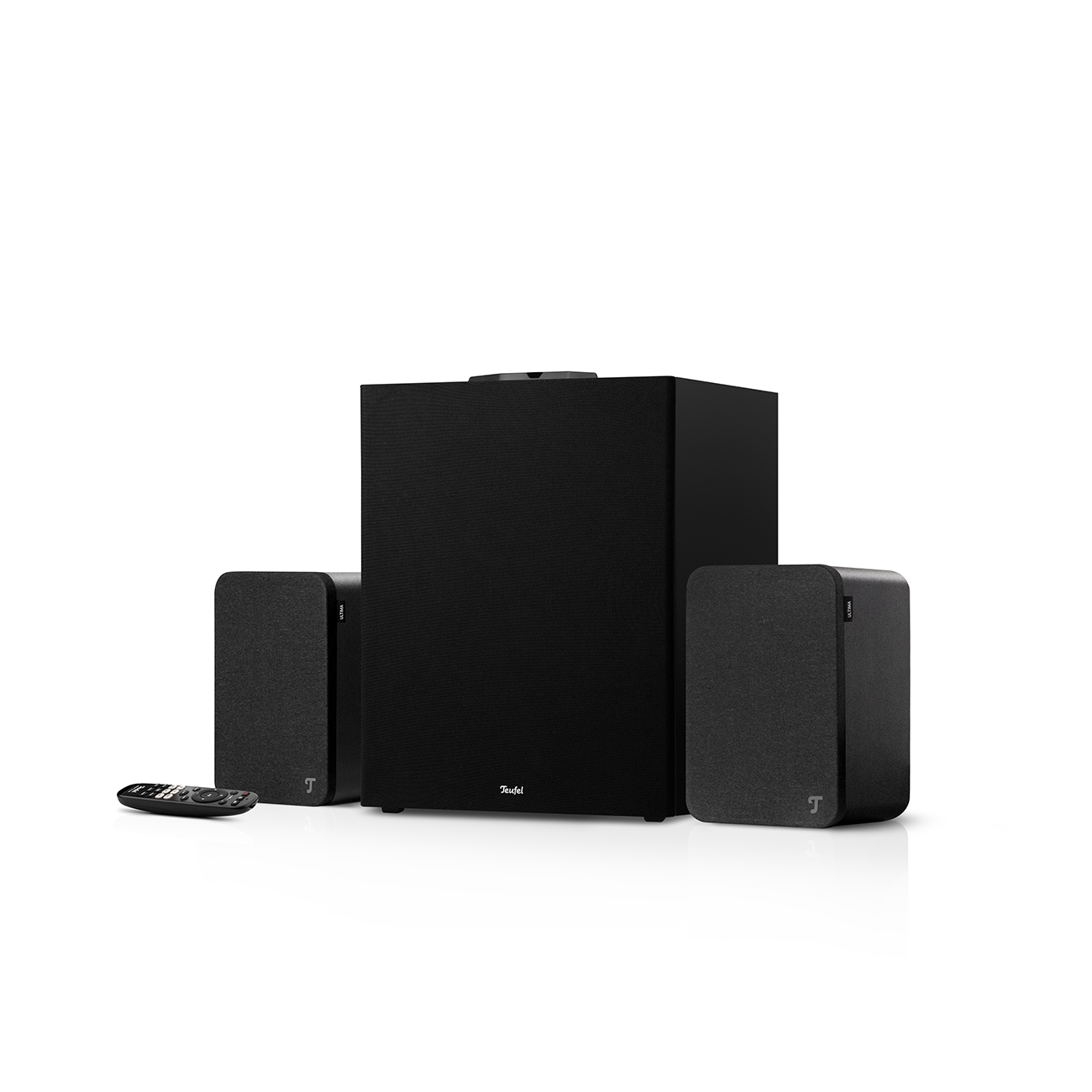 Ein schwarzes Lautsprechersystem mit Subwoofer und zwei Satellitenlautsprechern. Eine Fernbedienung liegt davor. Der Hintergrund ist weiß.
