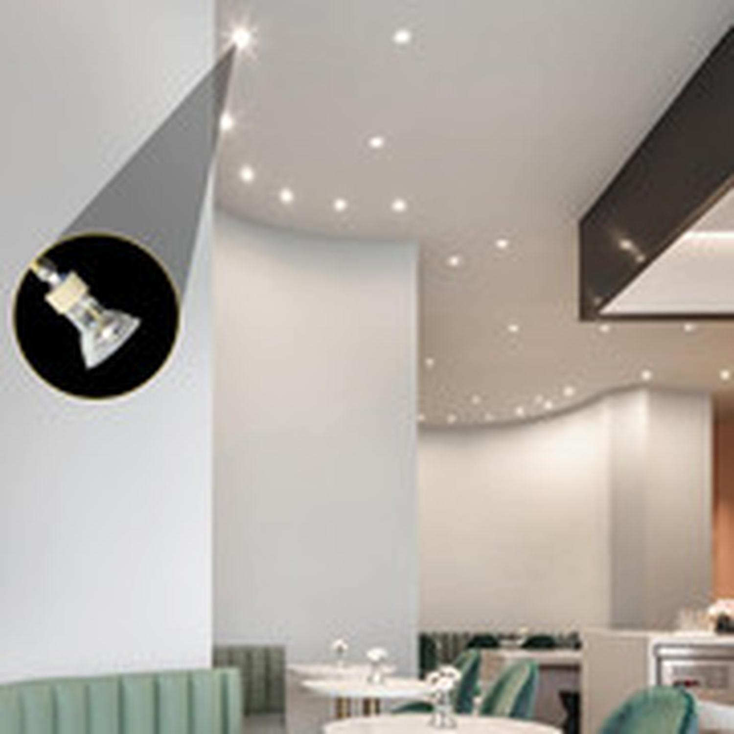 Wnętrze restauracji z wpuszczonymi światłami sufitowymi. Żarówka reflektora jest podświetlona w okręgu. Widoczne są stoły i krzesła.