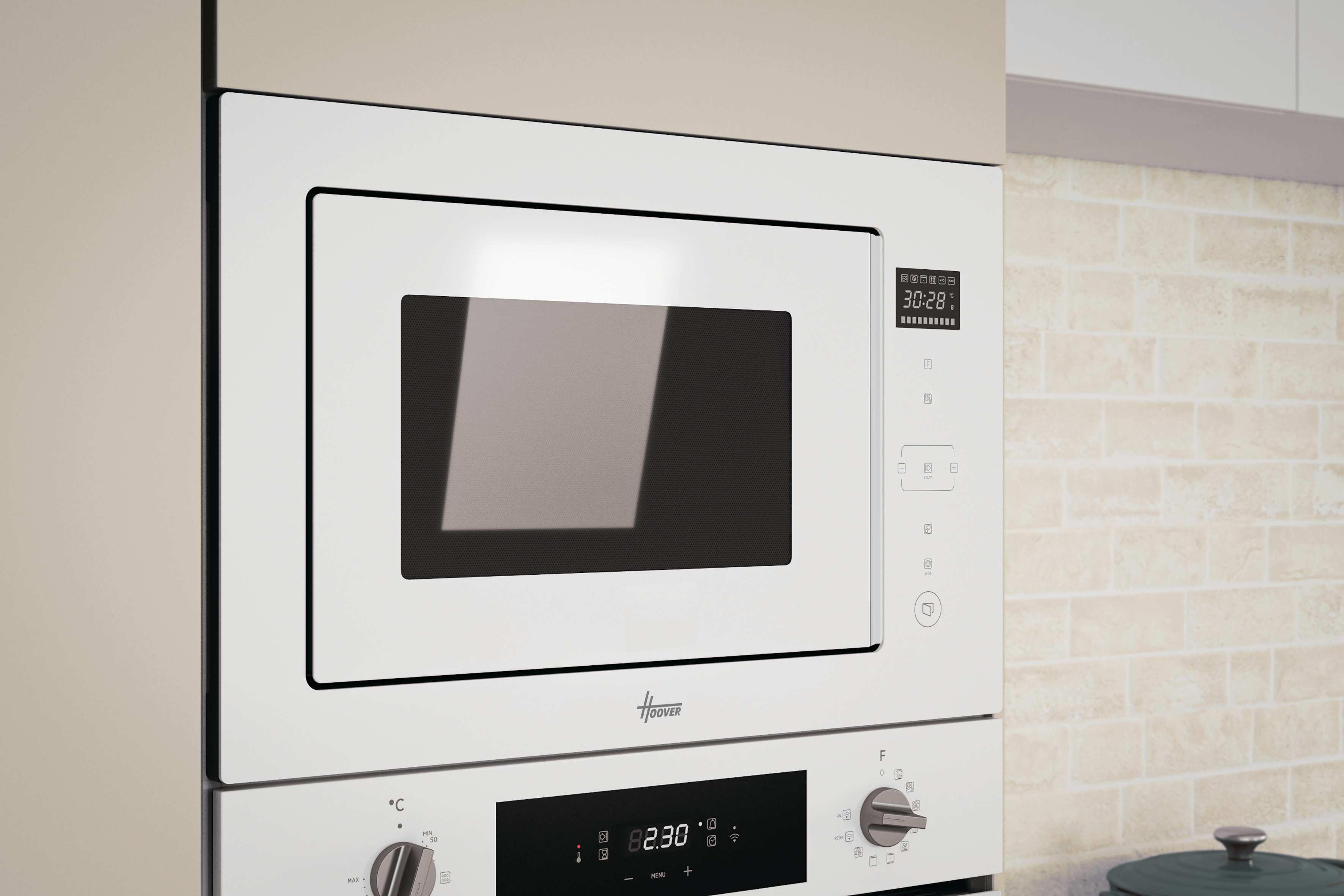 Biała kuchenka mikrofalowa i piekarnik Hoover, w kuchni. Wyświetlacz cyfrowy pokazuje czas. Beżowa ceglana ściana w tle.