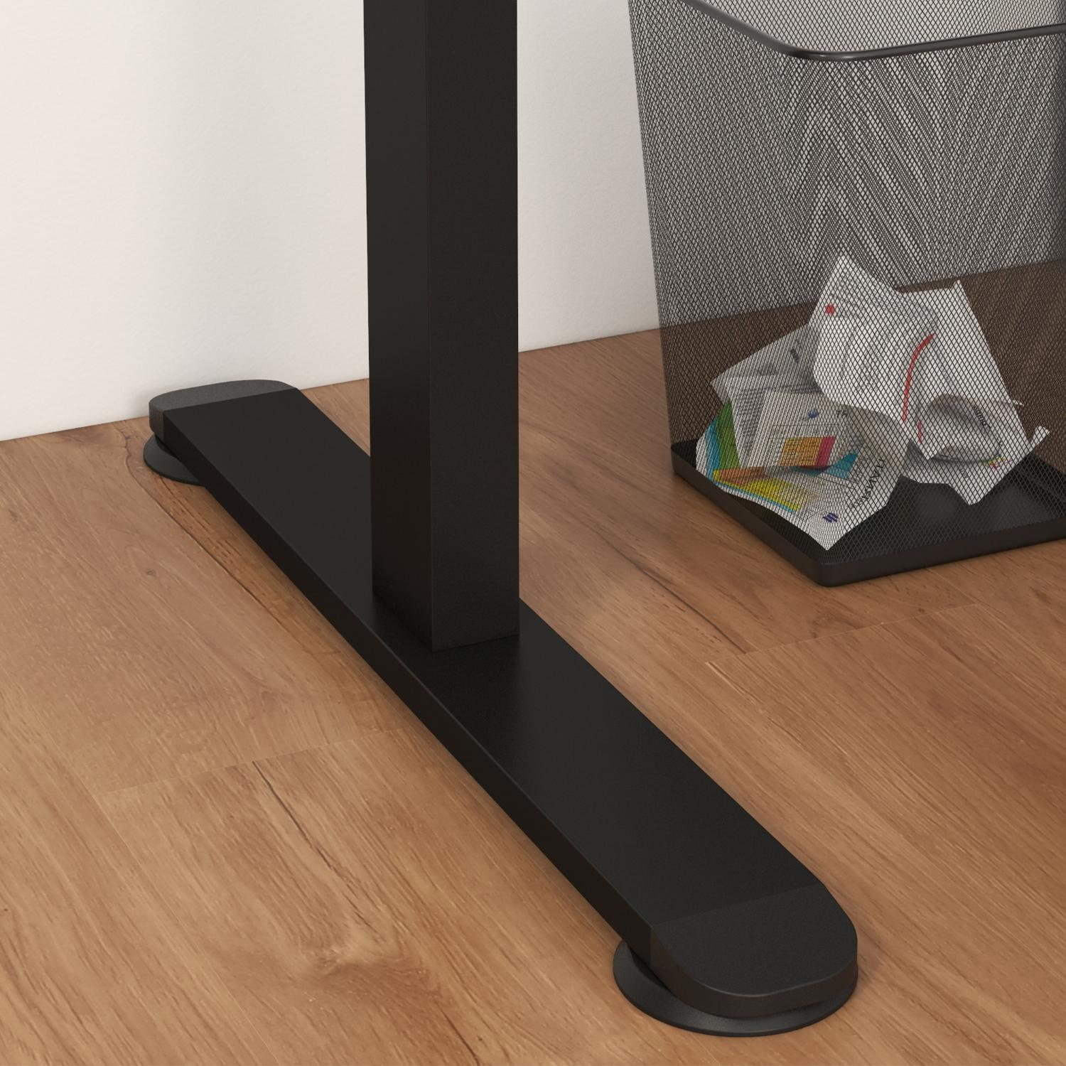 Ein schwarzes Schreibtischbein und -fuß auf einem Holzboden. Im Hintergrund ist ein Metall-Mülleimer mit zerknitterten Papieren zu sehen.
