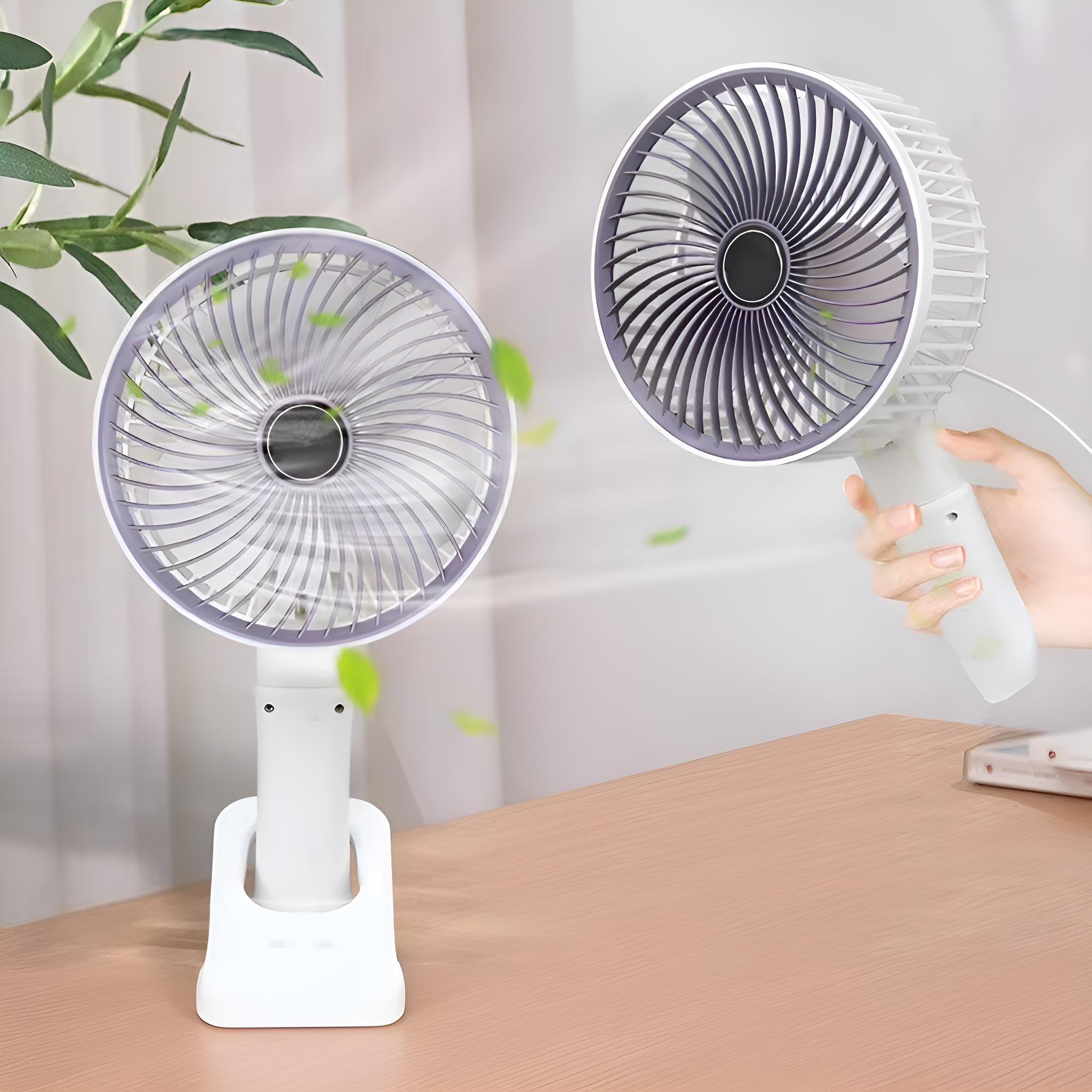 Zwei weiße und graue Ventilatoren auf einem Holztisch. Einer steht aufrecht, der andere wird von einer Hand gehalten.