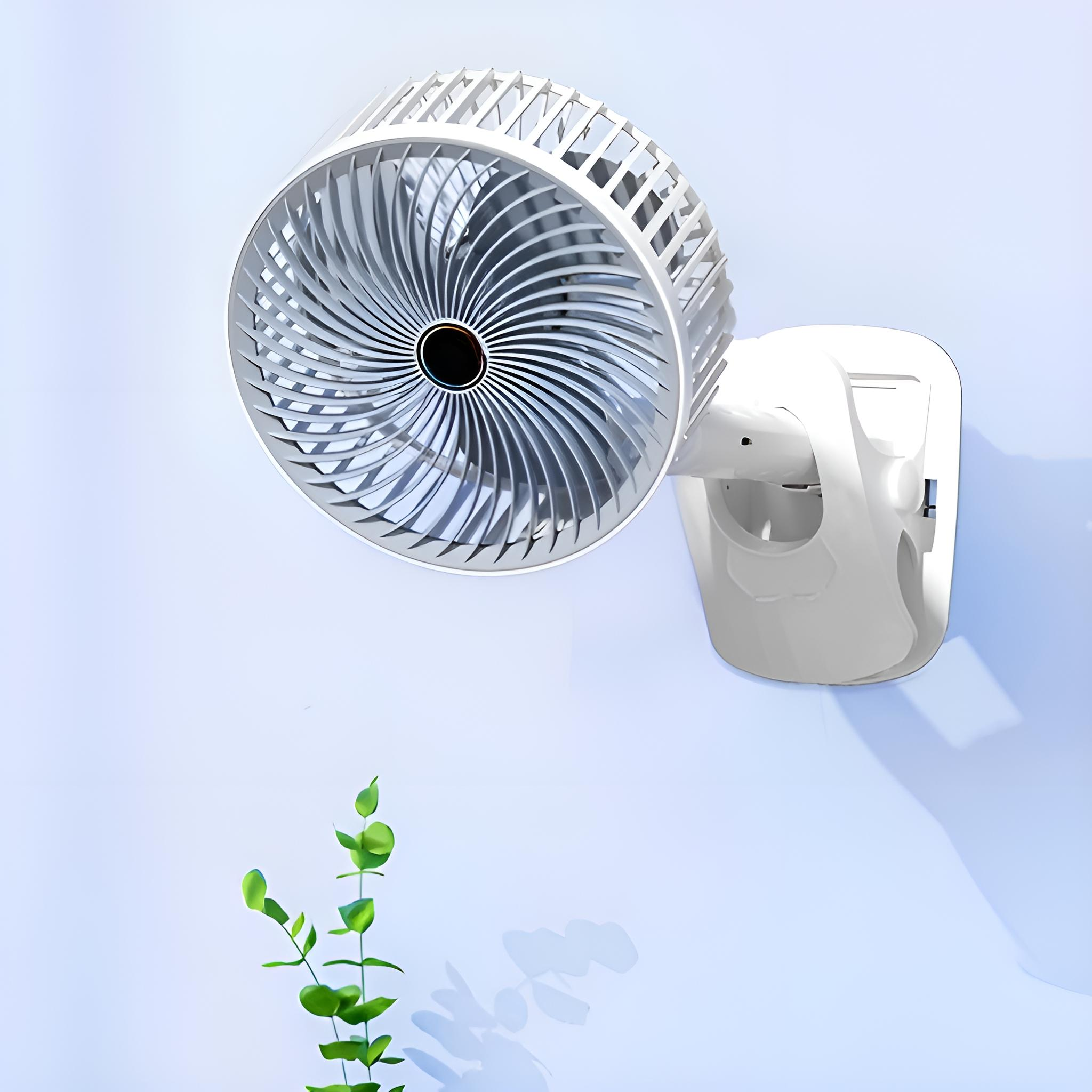 Ein weißer, an der Wand montierter Ventilator mit schwarzem Zentrum an einer blauen Wand. Grüne Blätter im Vordergrund.