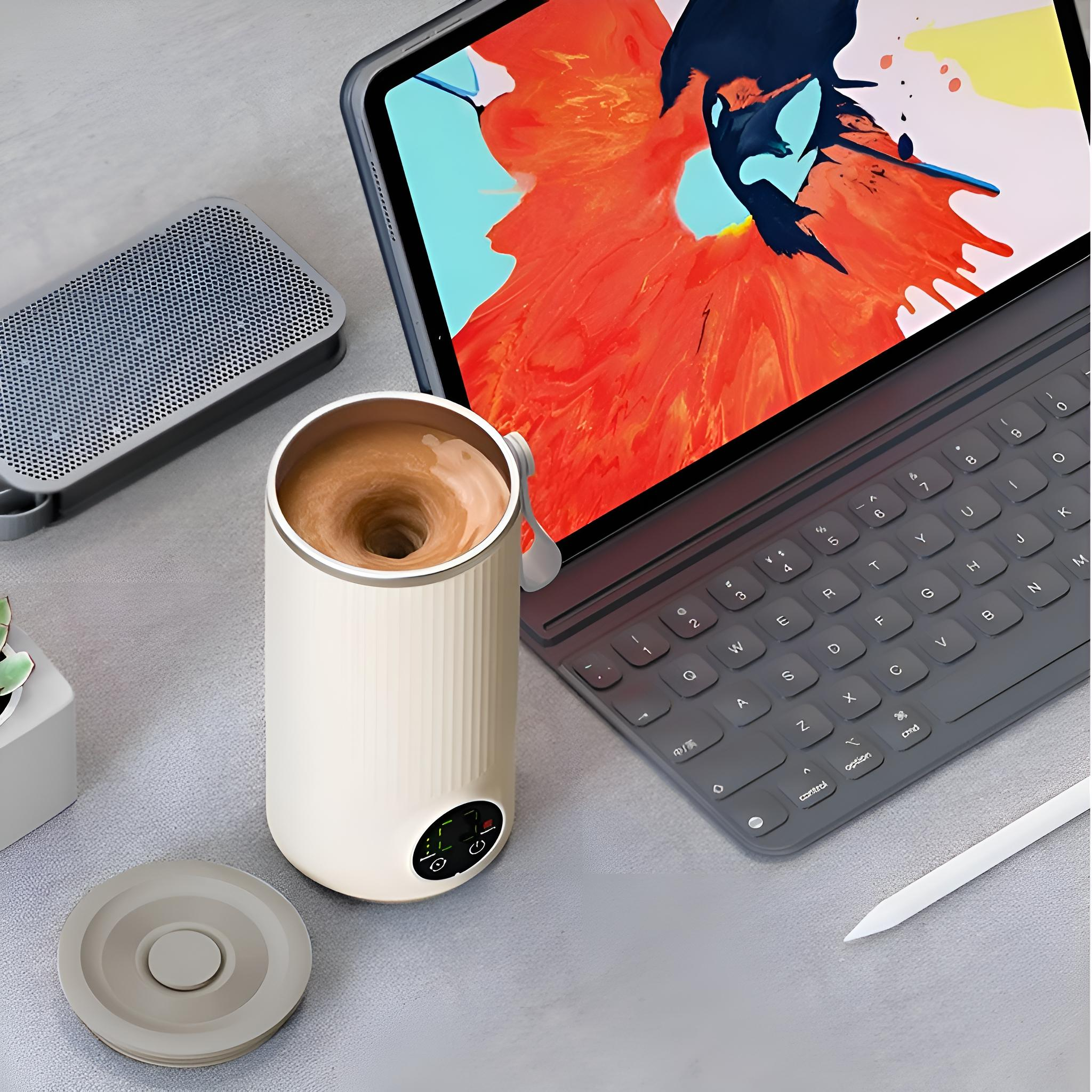 Ein cremefarbener Getränkemixer neben einem Tablet mit Kunstwerk, Tastatur, Lautsprecher und Bleistift auf grauem Untergrund.