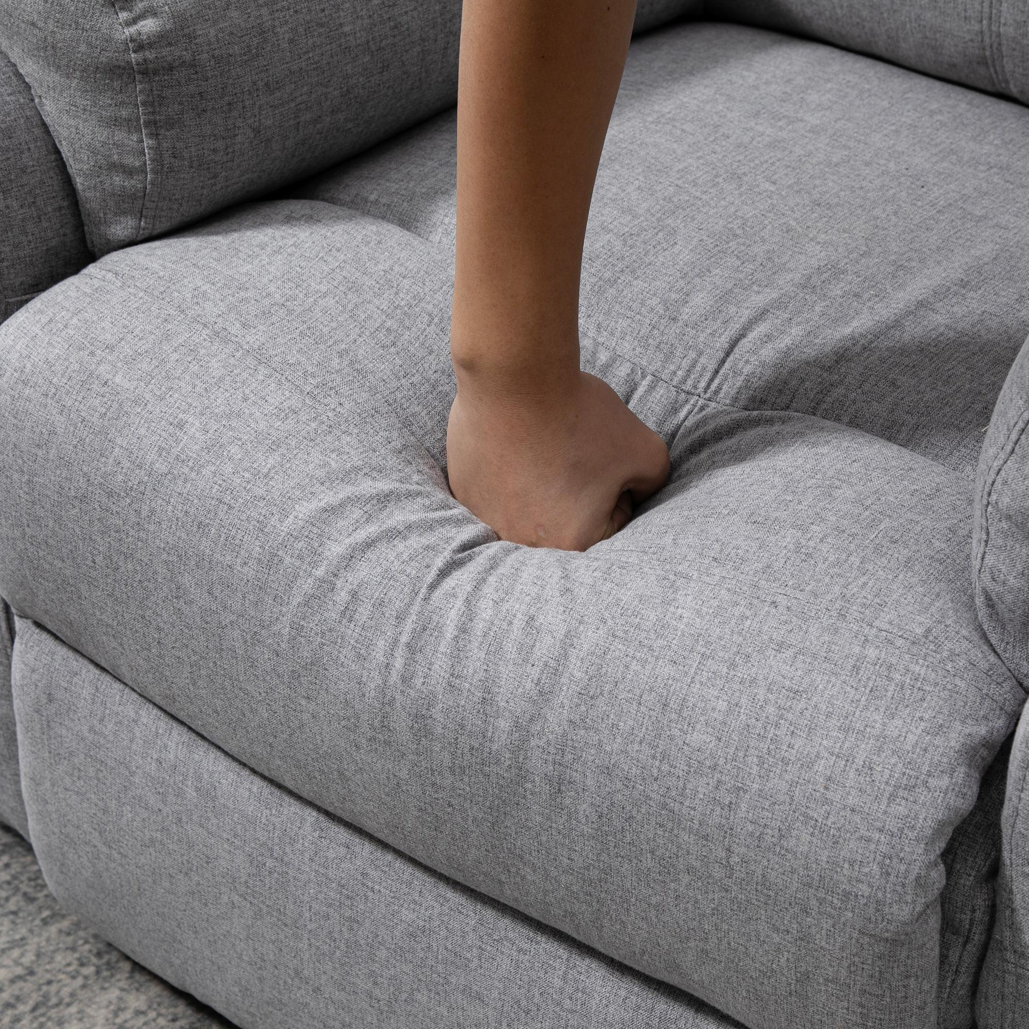Eine Hand drückt auf ein graues Sofakissen. Der Stoff zeigt den Abdruck der Hand.