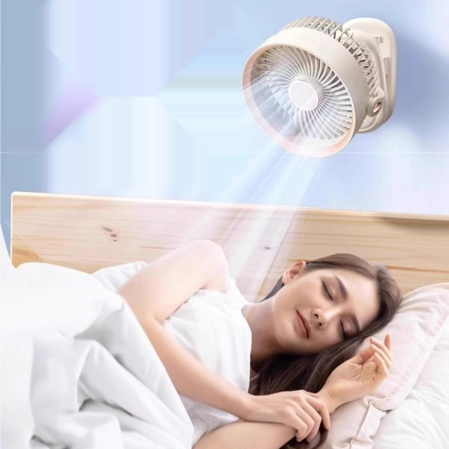Eine Frau schläft unter einer weißen Decke. Ein an der Wand montierter Ventilator bläst Luft auf sie. Der Hintergrund ist hellblau.