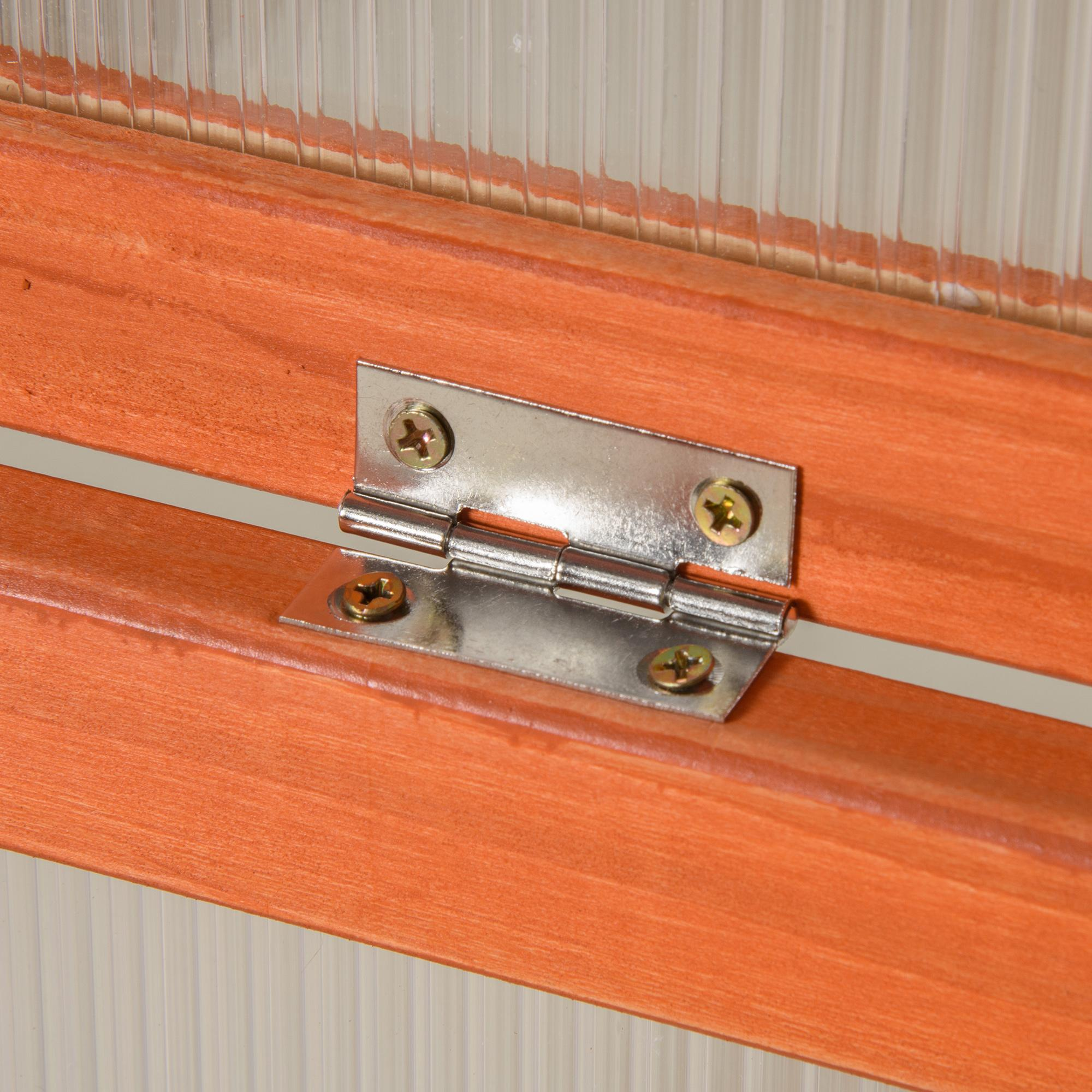Nahaufnahme eines Metallscharniers, das an orangefarbenen Holzplanken befestigt ist. Klare Kunststoffplatten im Hintergrund.
