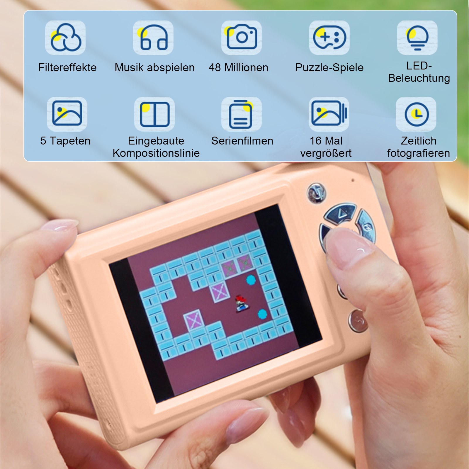 Eine Person hält eine pfirsichfarbene Digitalkamera, die ein Labyrinthspiel anzeigt. Die Kamera hat mehrere Funktionssymbole. Der Hintergrund ist aus Holz.