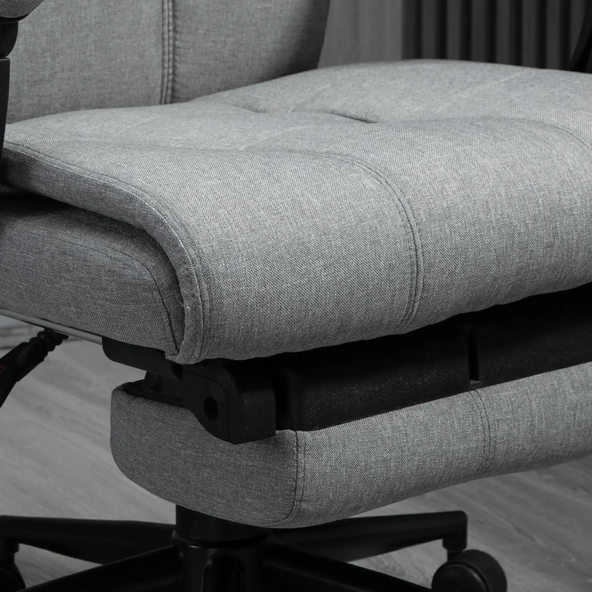 Nahaufnahme eines grauen Bürostuhls. Sitz und Rückenlehne sind aus grauem Stoff mit Steppdetails. Schwarzes Gestell mit Rollen.