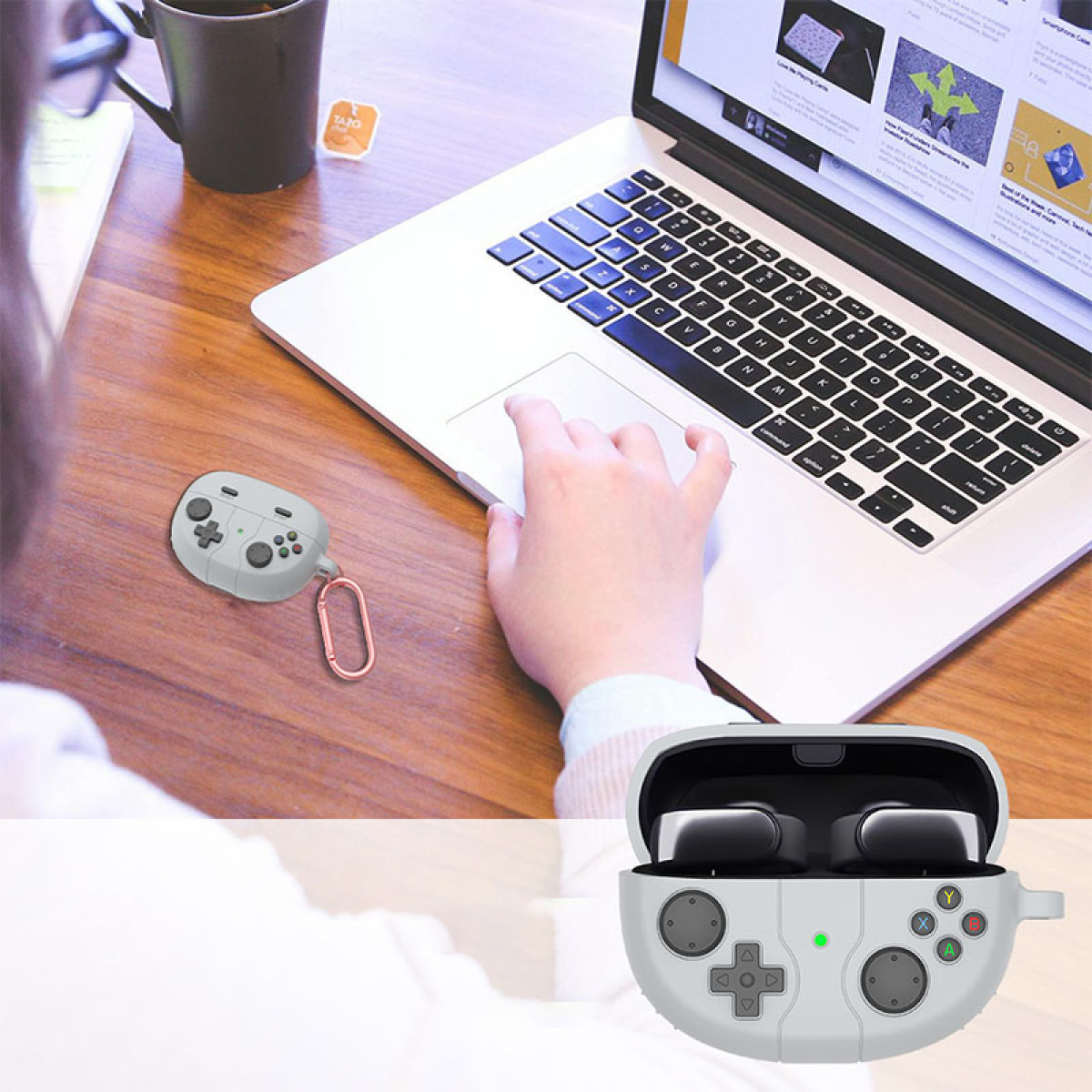Eine Person benutzt einen Laptop, in der Nähe einer grauen Gamepad-Hülle. Das Etui ist offen und zeigt schwarze Ohrhörer.