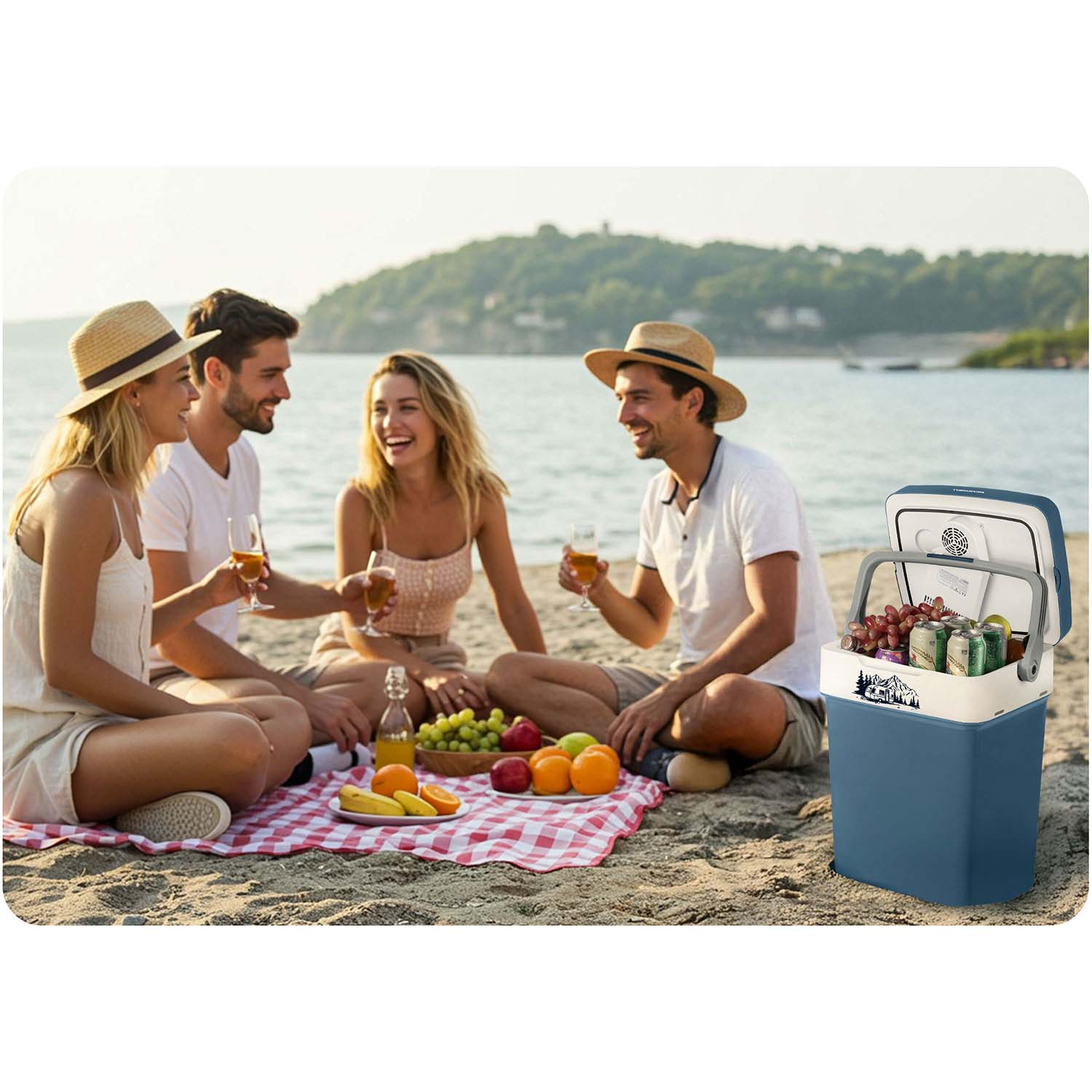 Cztery osoby na pikniku na plaży, pijące. Chłodziarka z napojami i owocami na kraciastej narzucie. W tle woda i wzgórze.