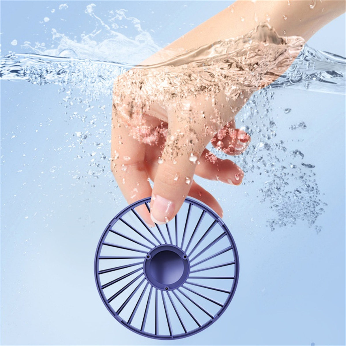 Hand hält einen lila Ventilator unter Wasser. Wasser spritzt um die Hand und den Ventilator herum und erzeugt Blasen.