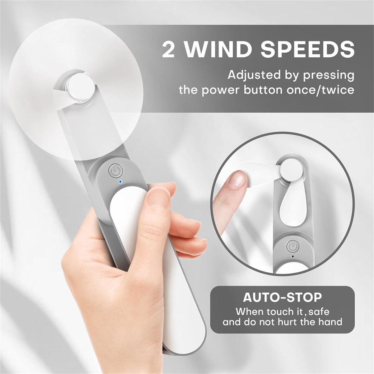 Eine Person hält einen grau-weißen Mini-Ventilator. Der Ventilator hat zwei Windgeschwindigkeiten und eine Auto-Stopp-Funktion.
