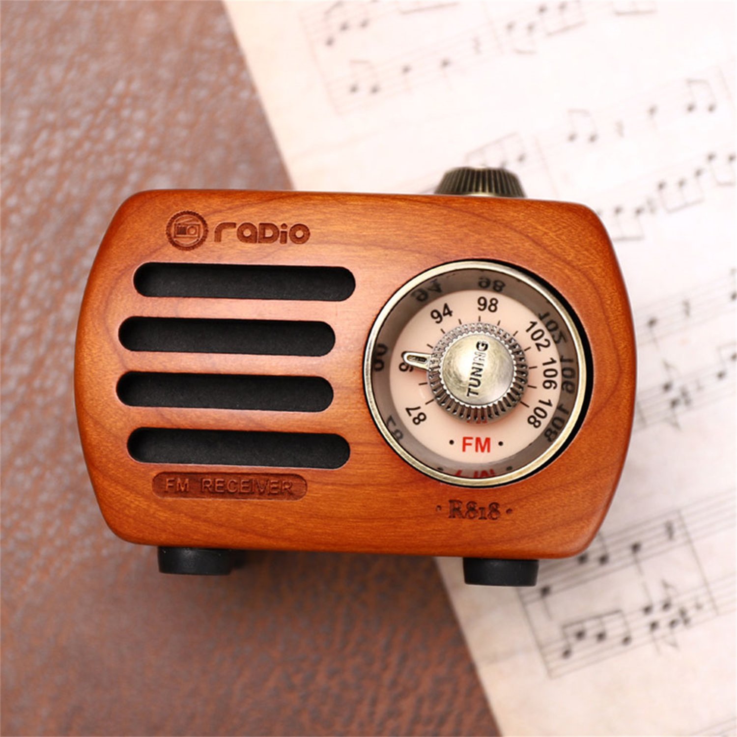 Ein Retro-Radio aus Holz steht auf einer Oberfläche. Das Radio hat ein Wahlrad und Lautsprecherlöcher. Noten befinden sich im Hintergrund.