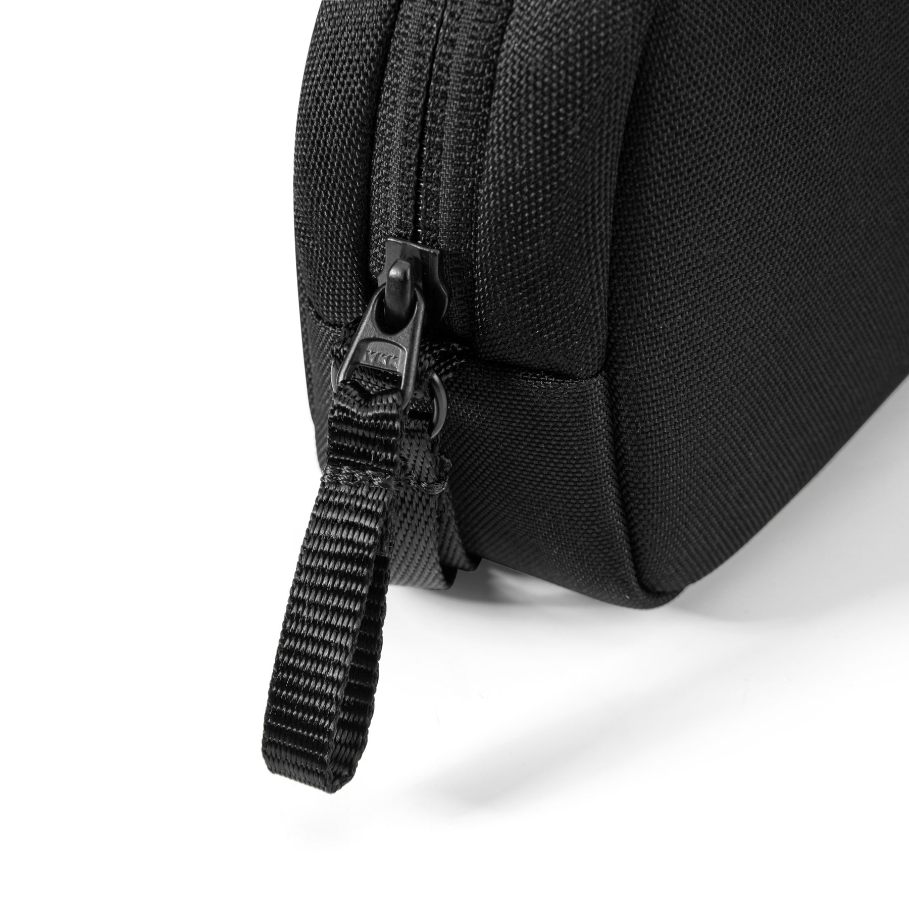 Nahaufnahme einer schwarzen Tasche mit Reißverschluss. Der Reißverschluss ist sichtbar. Der Hintergrund ist weiß.