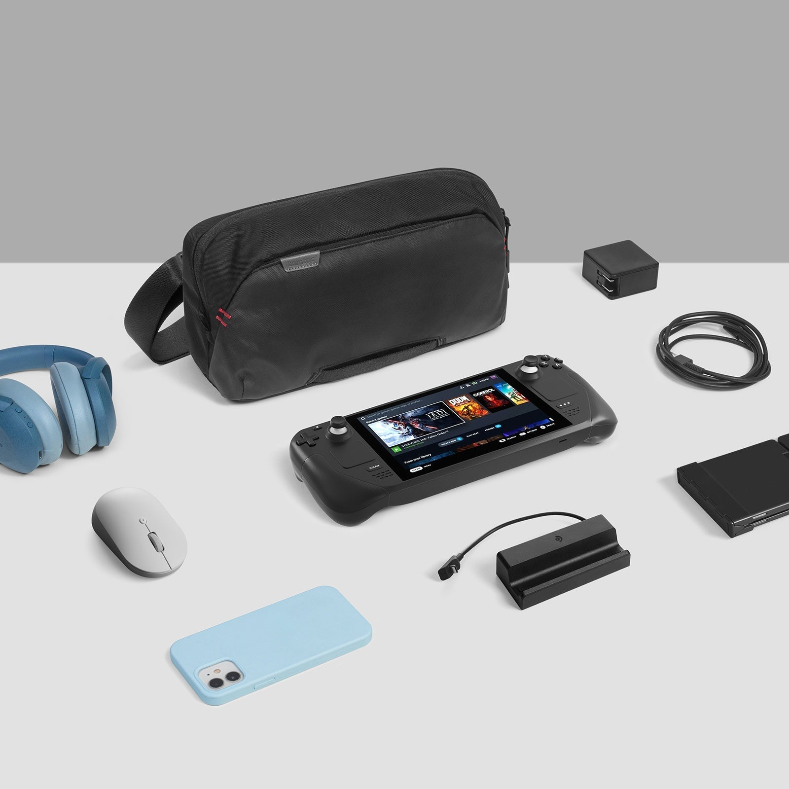 Urządzenie do gier z akcesoriami, w tym torbą, słuchawkami, myszą, etui, ładowarką i kablem, na białej powierzchni.