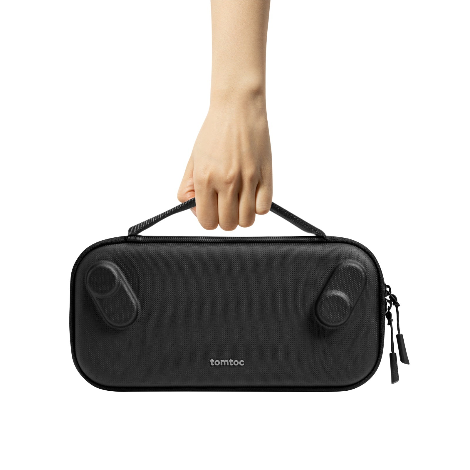 Ręka trzyma czarną torbę transportową. Torba ma uchwyt i zamki błyskawiczne. Tło jest białe.