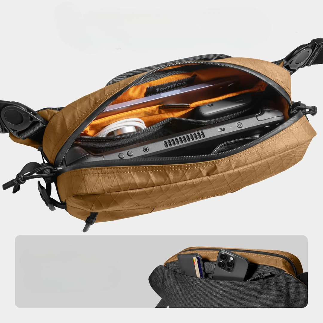 Brązowa torba jest otwarta, ukazując elektronikę i akcesoria. Wewnątrz widoczny jest tablet, ładowarka i urządzenie do gier. Mniejsza przegródka pokazuje telefony.