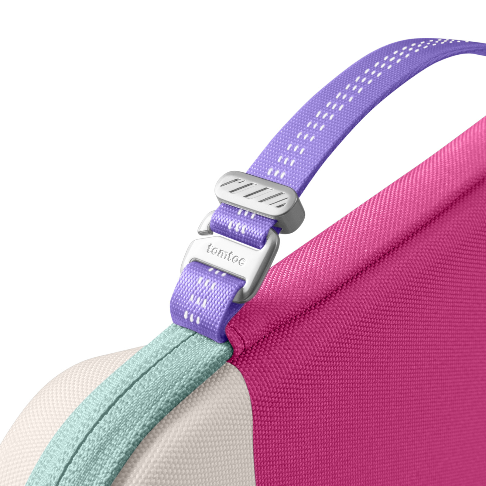 Zbliżenie torby z fioletowym paskiem i srebrną klamrą. Torba jest różowa, biała i turkusowa.